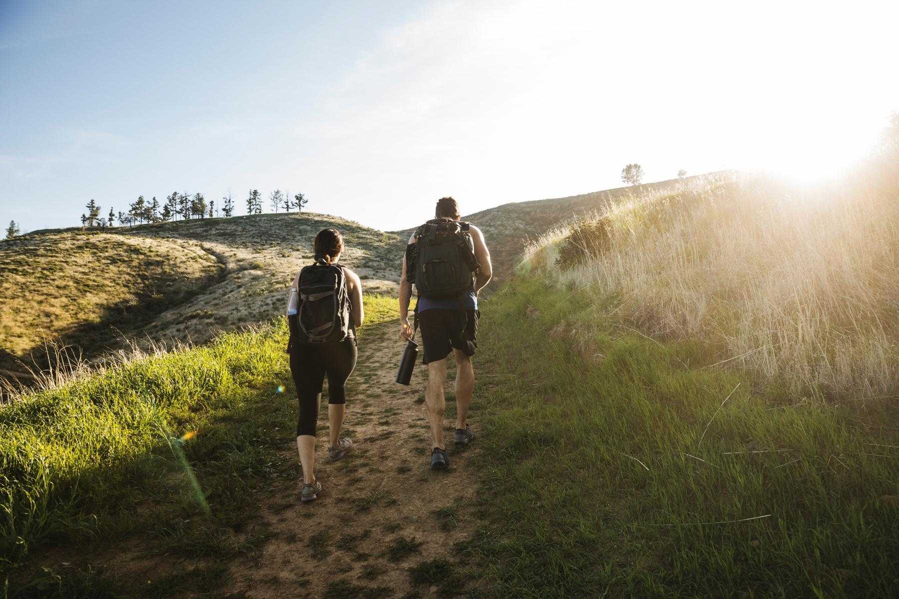 Man and woman with backpacks on hiking up hill.