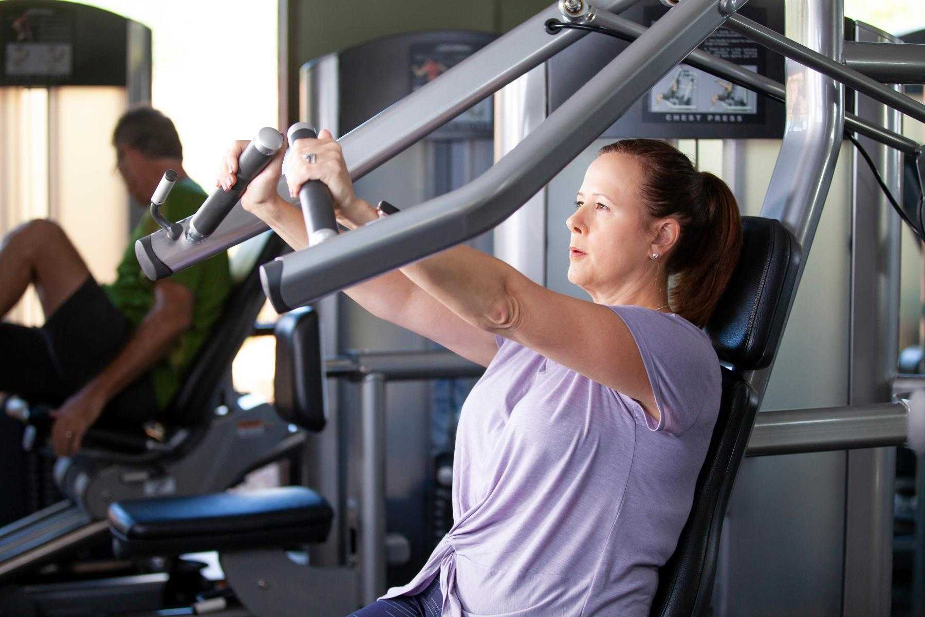woman using chest press machine in gym