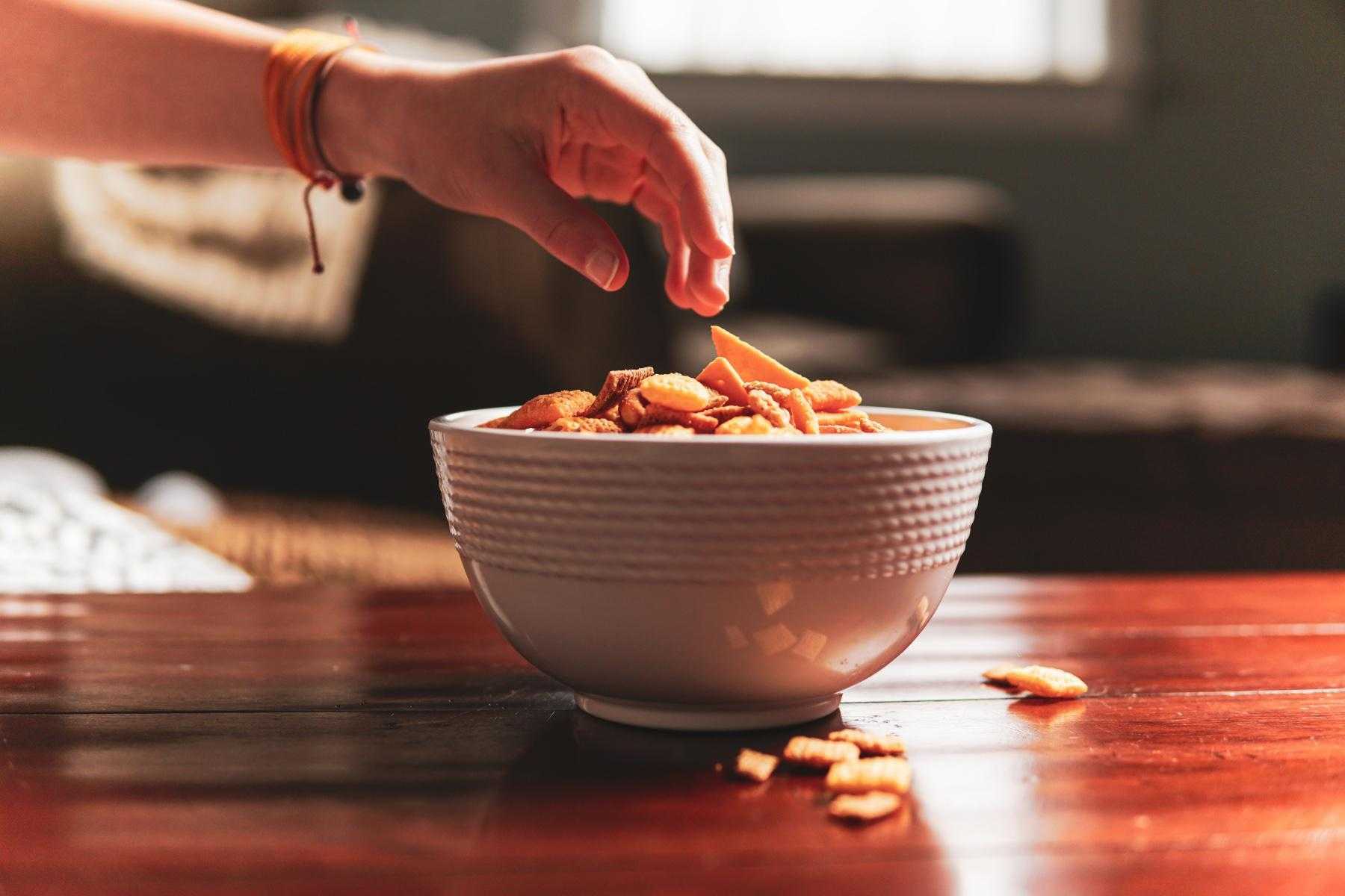 Hand reaching for bowl of snacks.