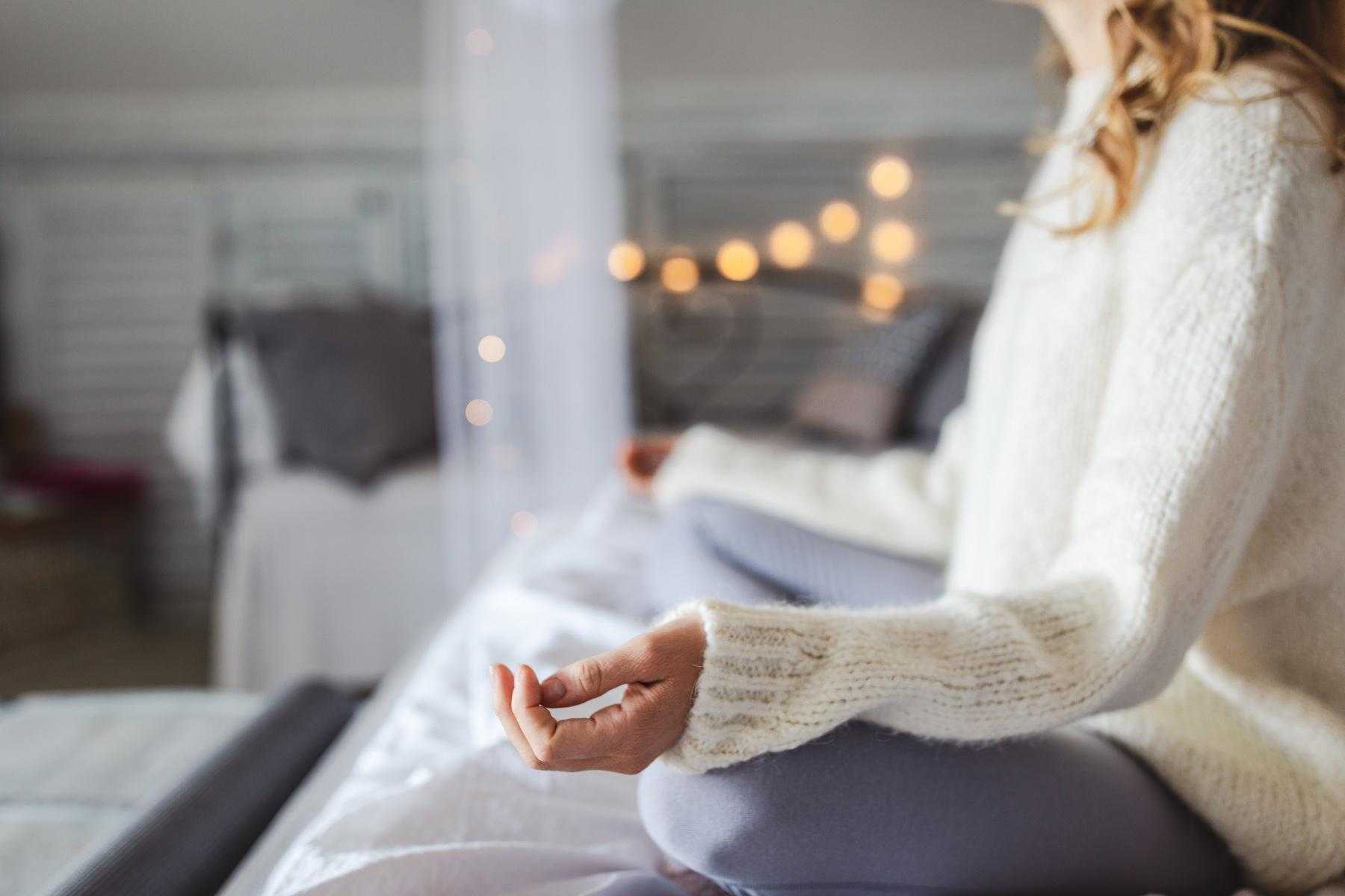 Woman meditating on her bed.