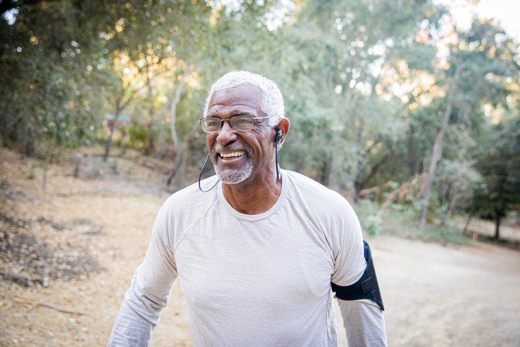 Man walking outside listening to music and smiling.