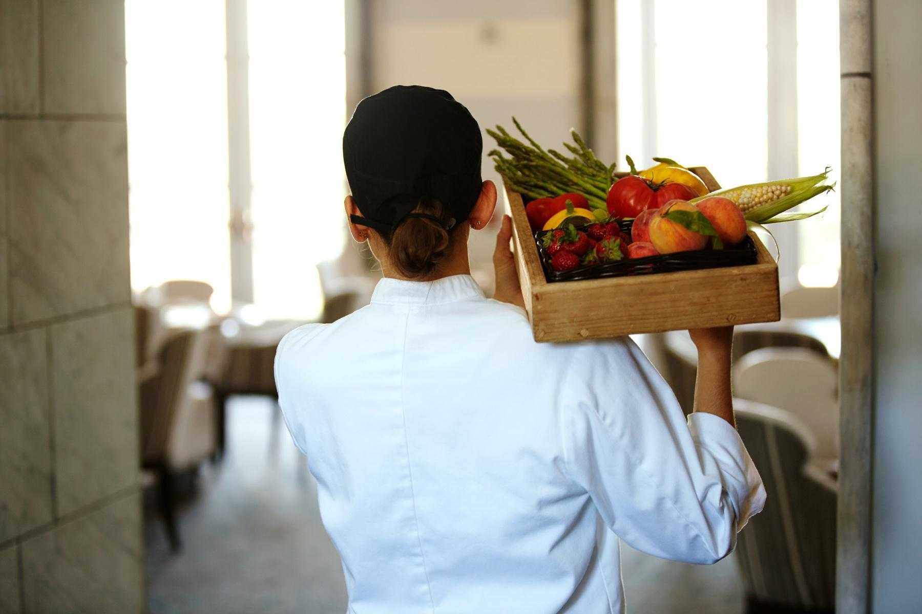 chef carrying box of fresh vegetables on shoulder