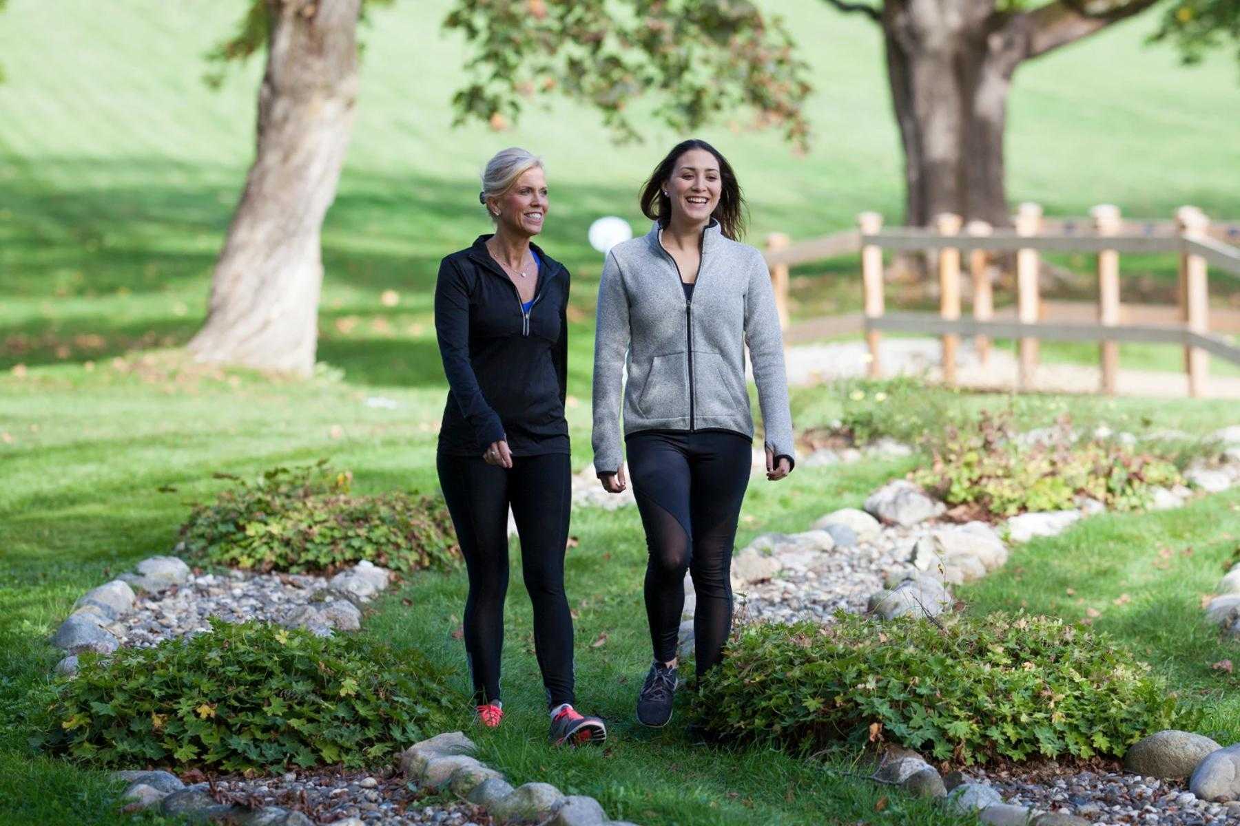 mother and daughter smiling while walking through labyrinth path with rock edges on grass