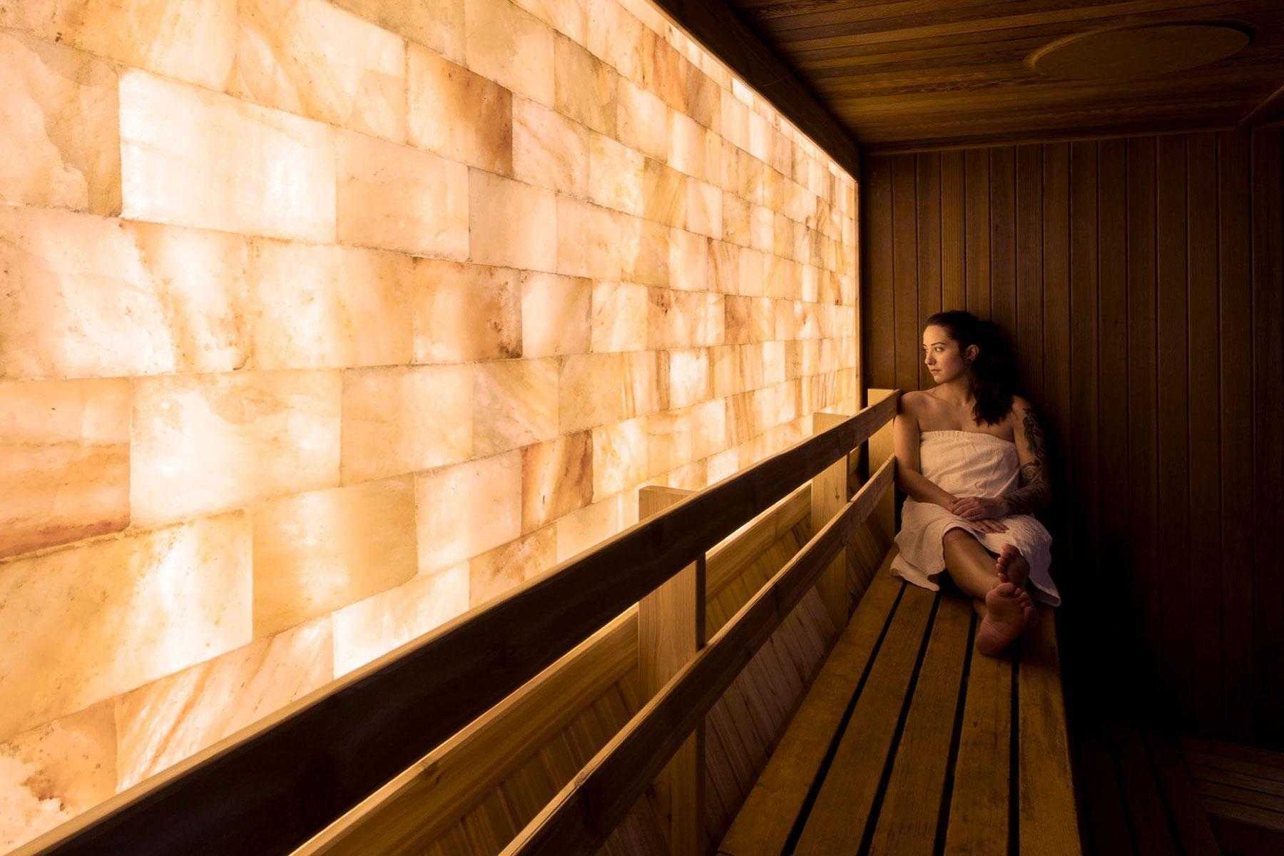 Woman sitting in sauna with salt wall.