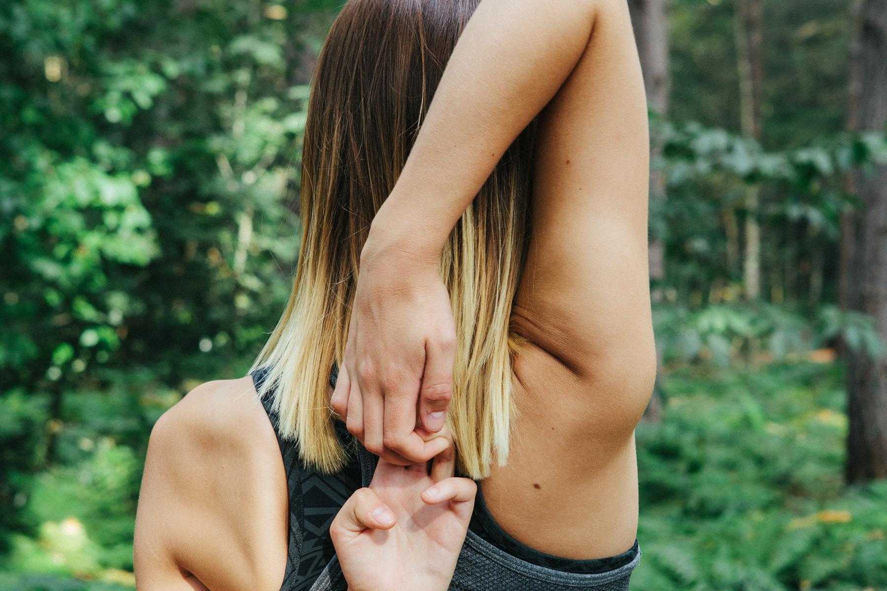 woman standing outside with hands linked behind head while stretching