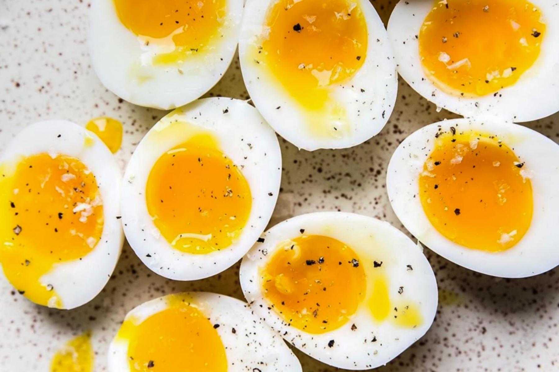 close-up overhead image of soft boiled eggs cut in half with salt and pepper on them