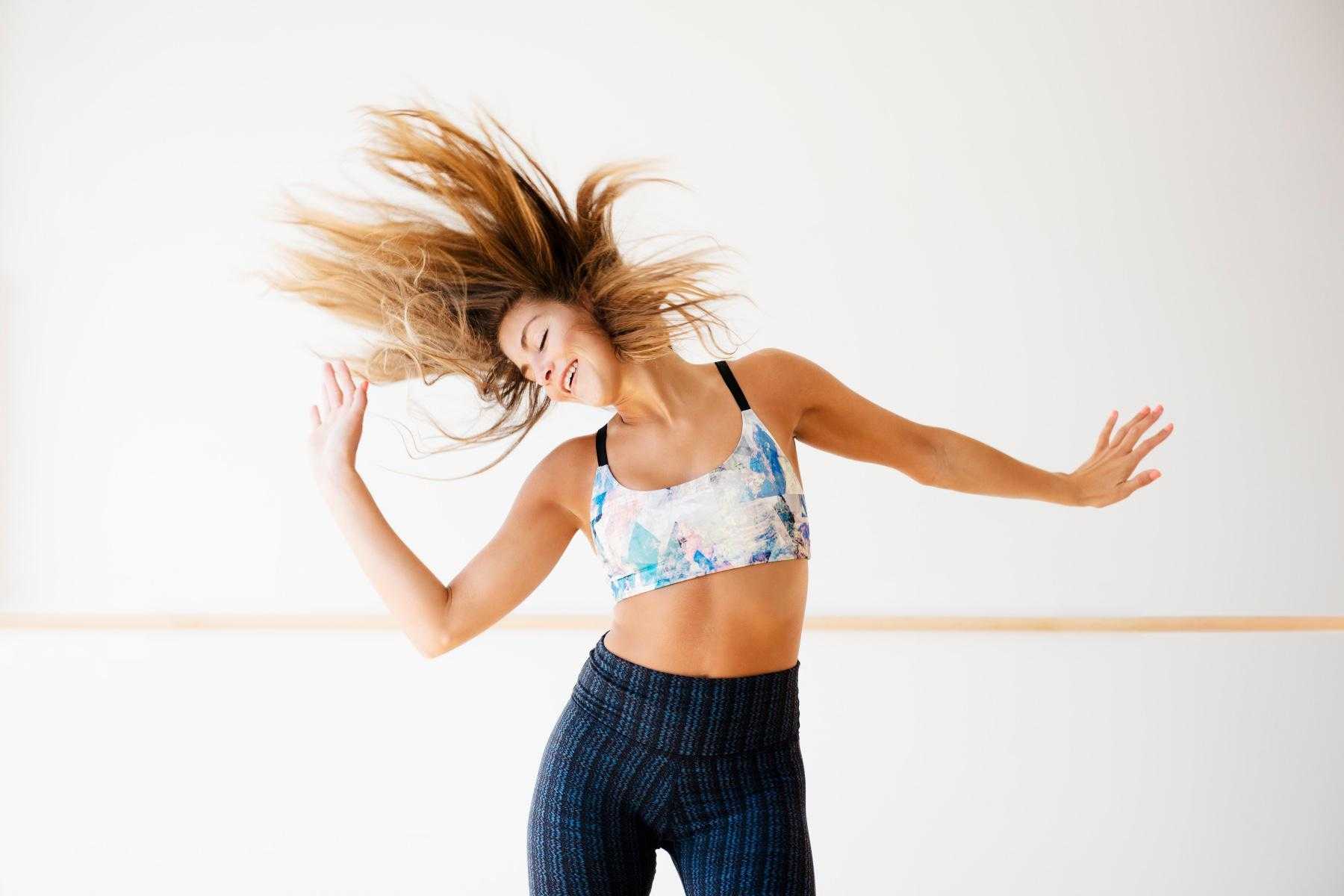 woman mid-dance move throwing hands to the side and flipping hair