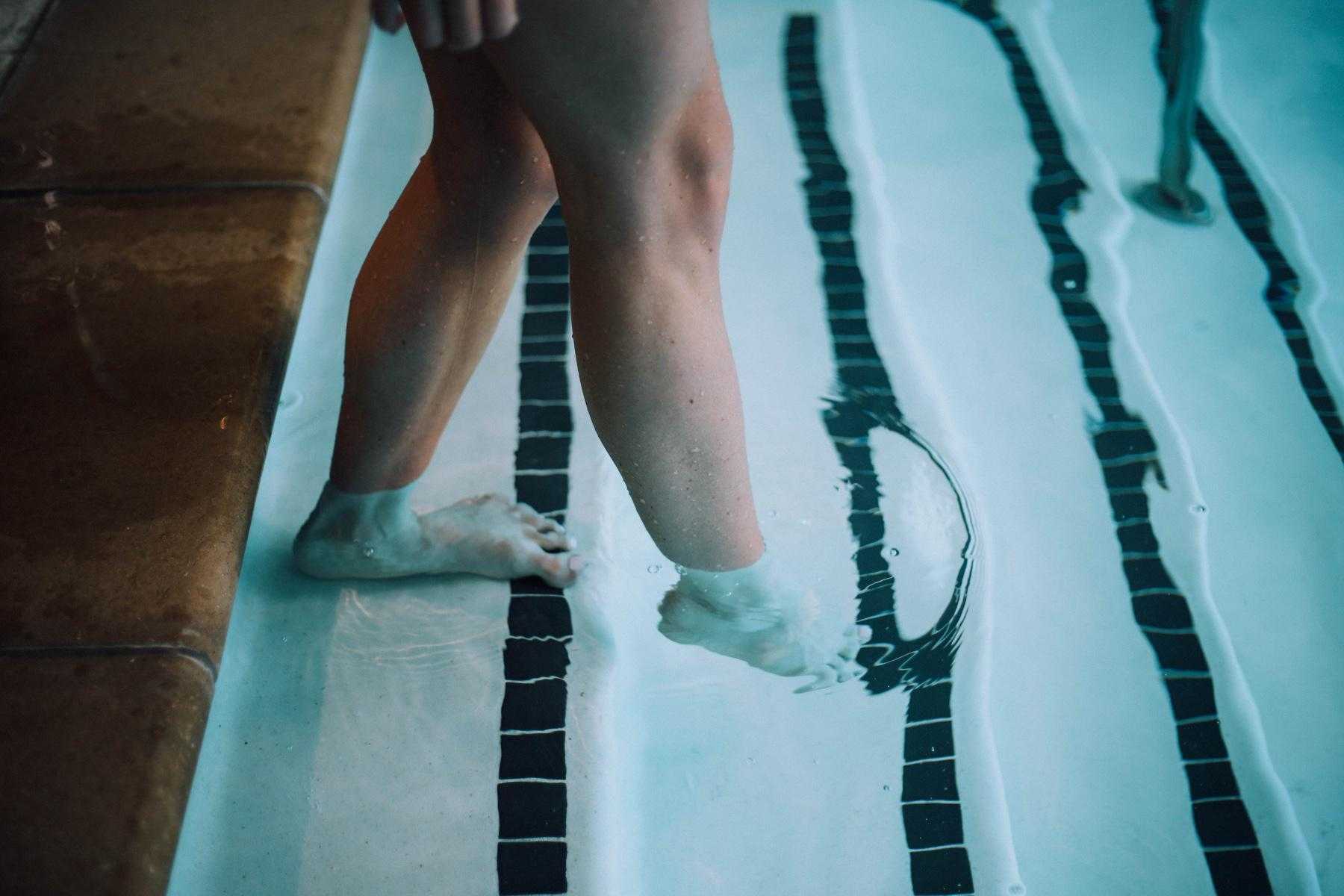 close-up of a woman's feet stepping down into pool