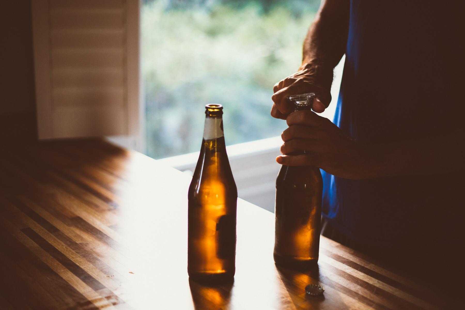 close-up of man opening two bottles of beer
