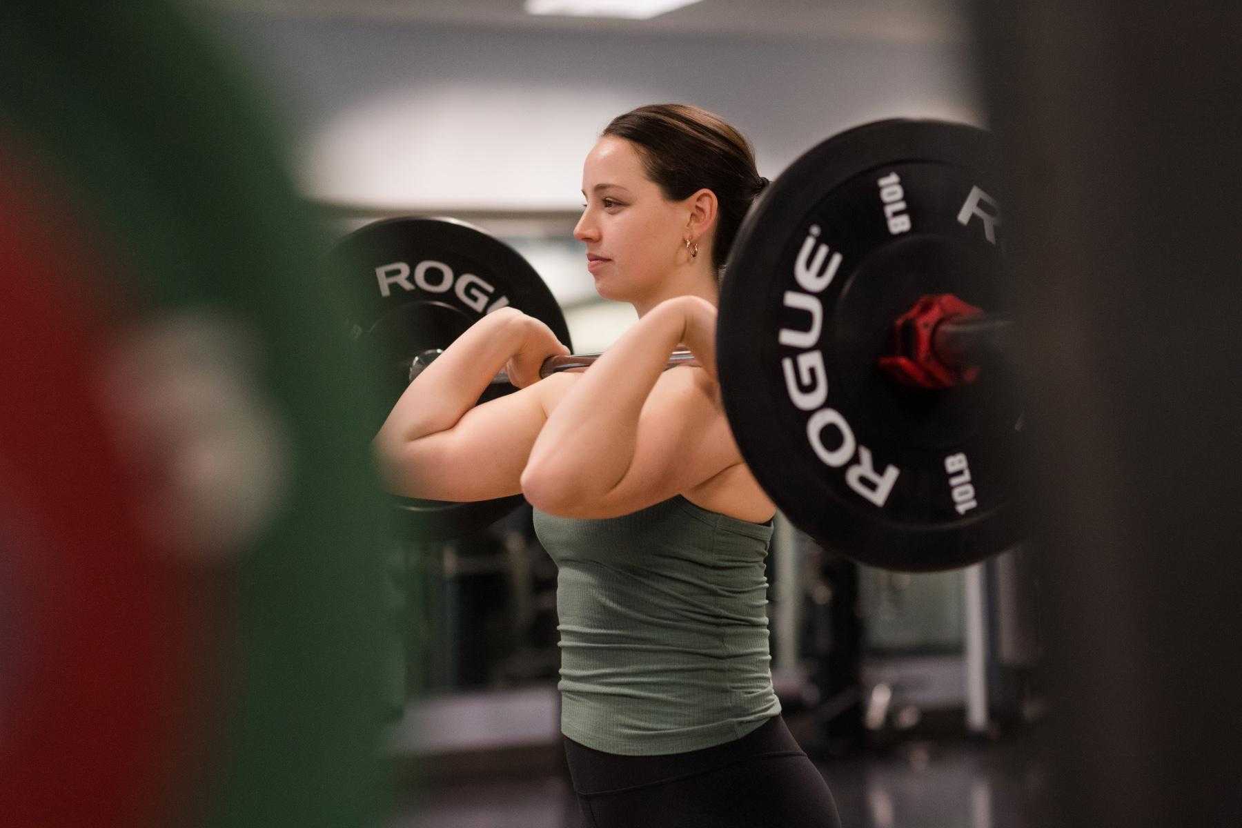 woman holding loaded barbell in front rack position