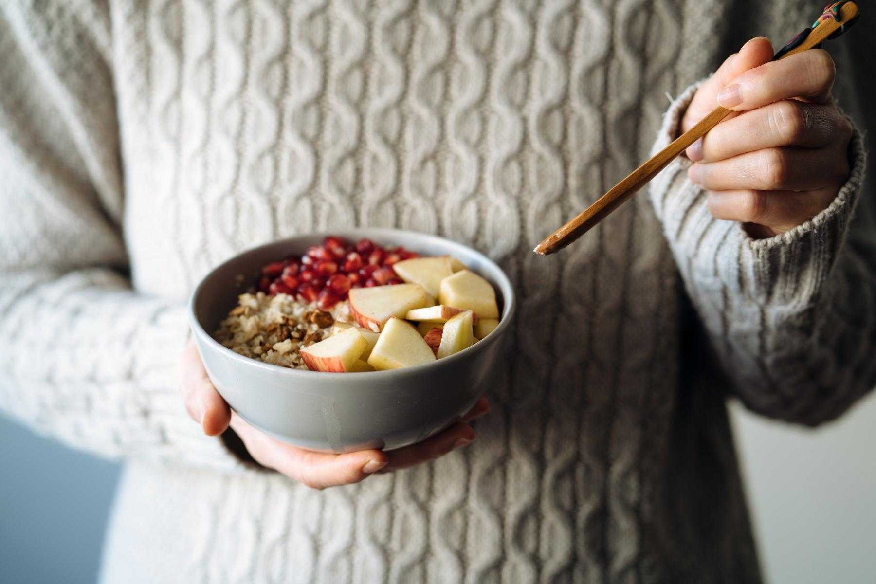 close-up of woman holding bowl of boats with apples on top