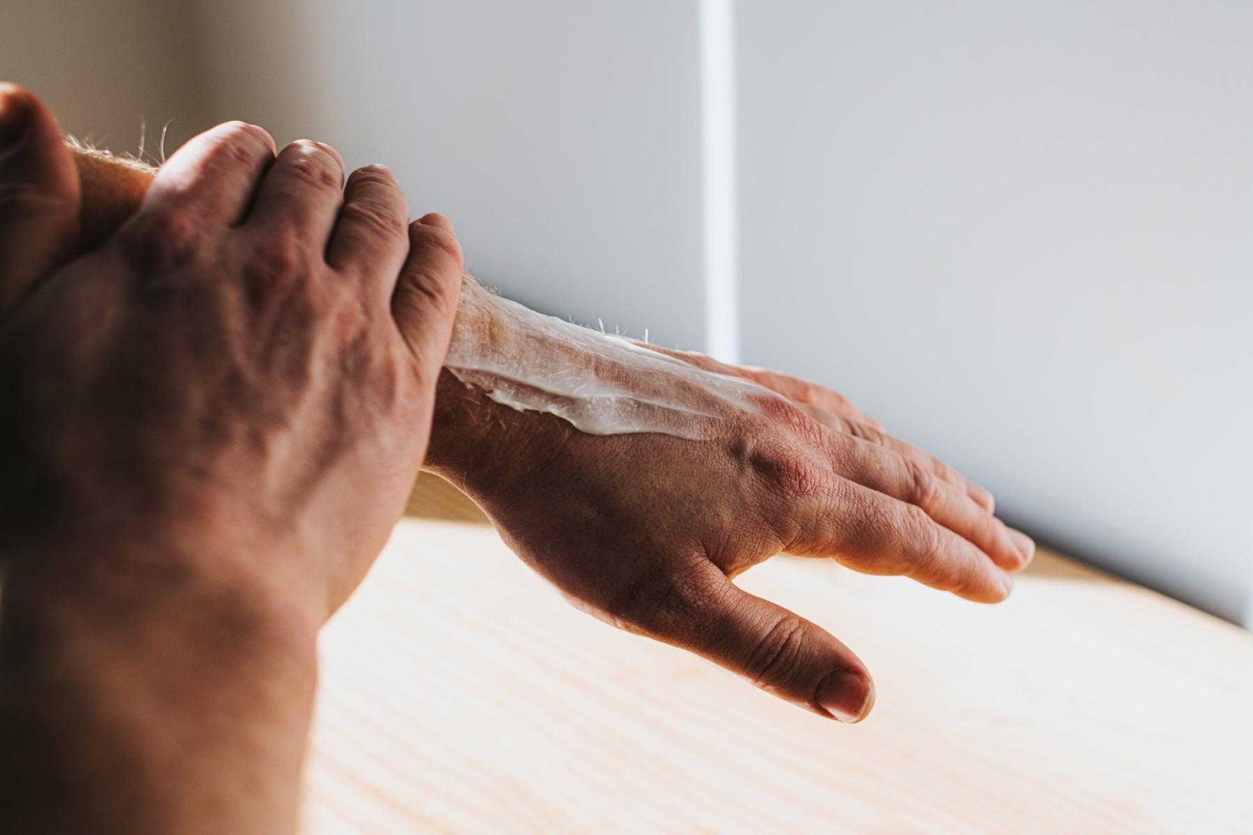A man rubbing shea butter into his arm.