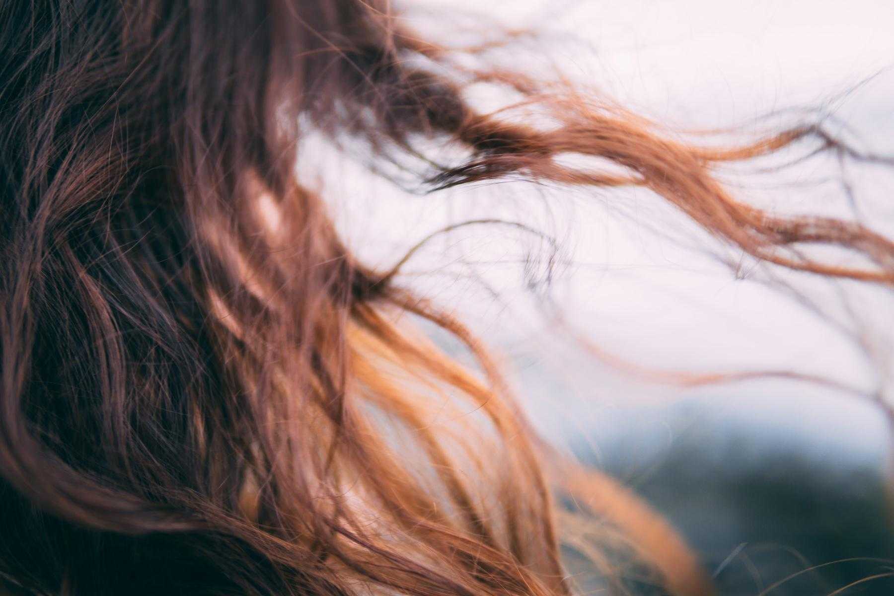 A close-up of a brunette woman's hair blowing in the wind.