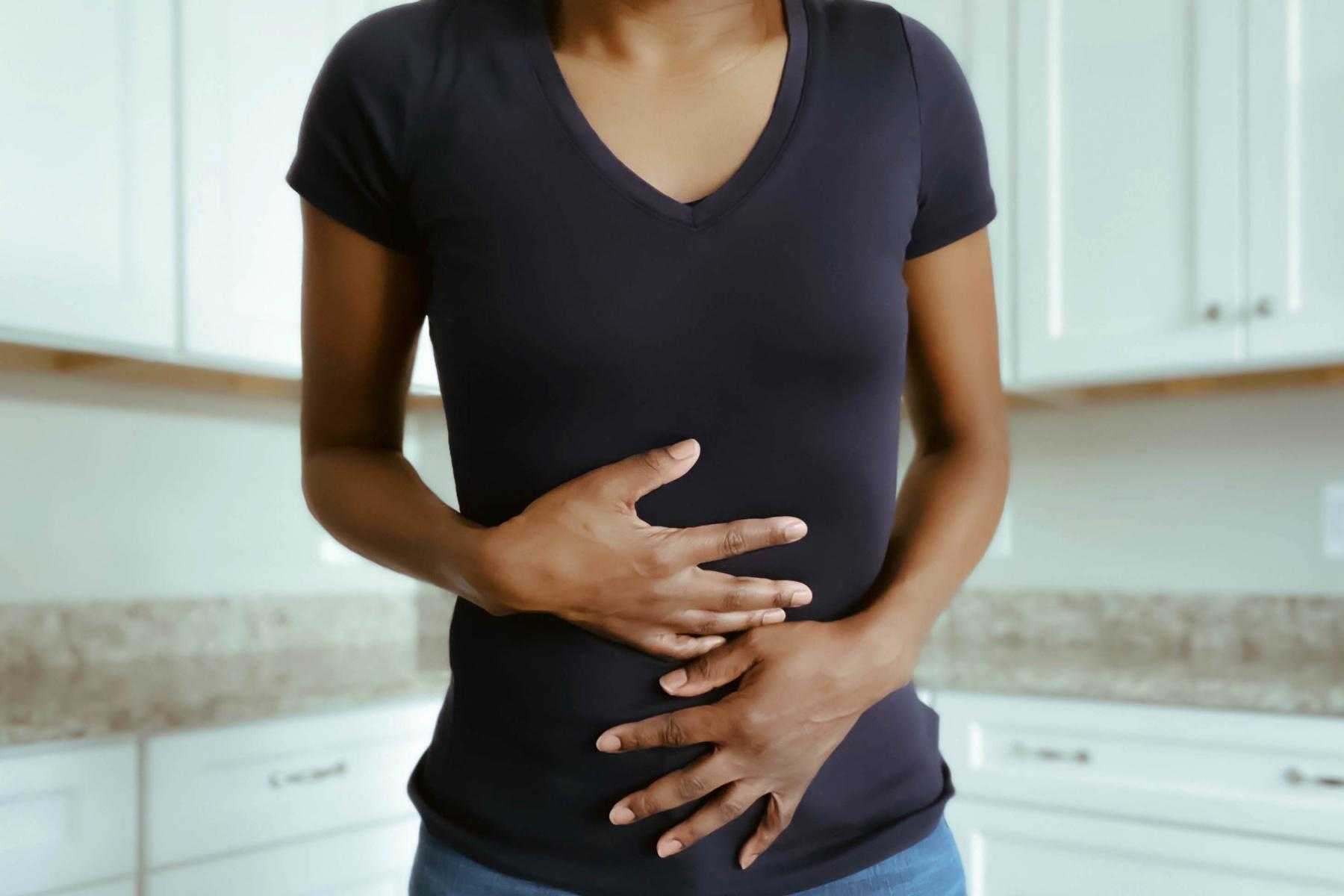 Woman with hands on stomach in pain.