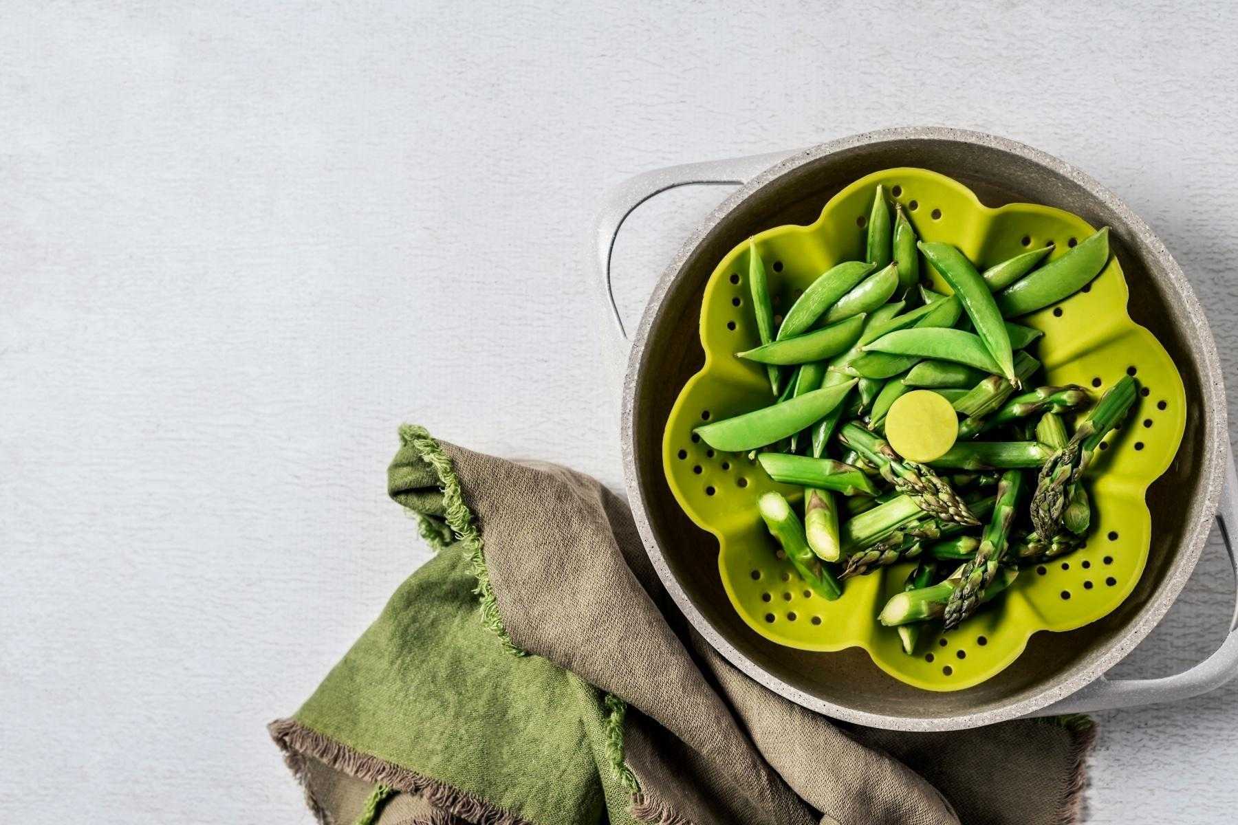 Overhead view of peas in a green vegetable steamer.
