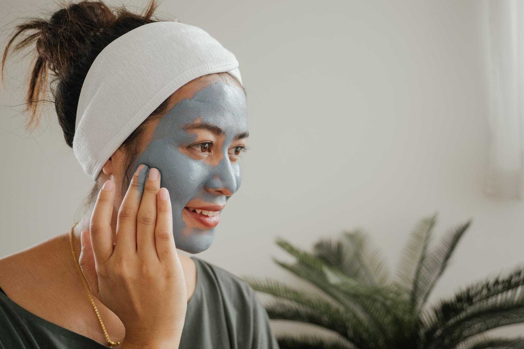 A young woman in her bathroom applying a facemask.
