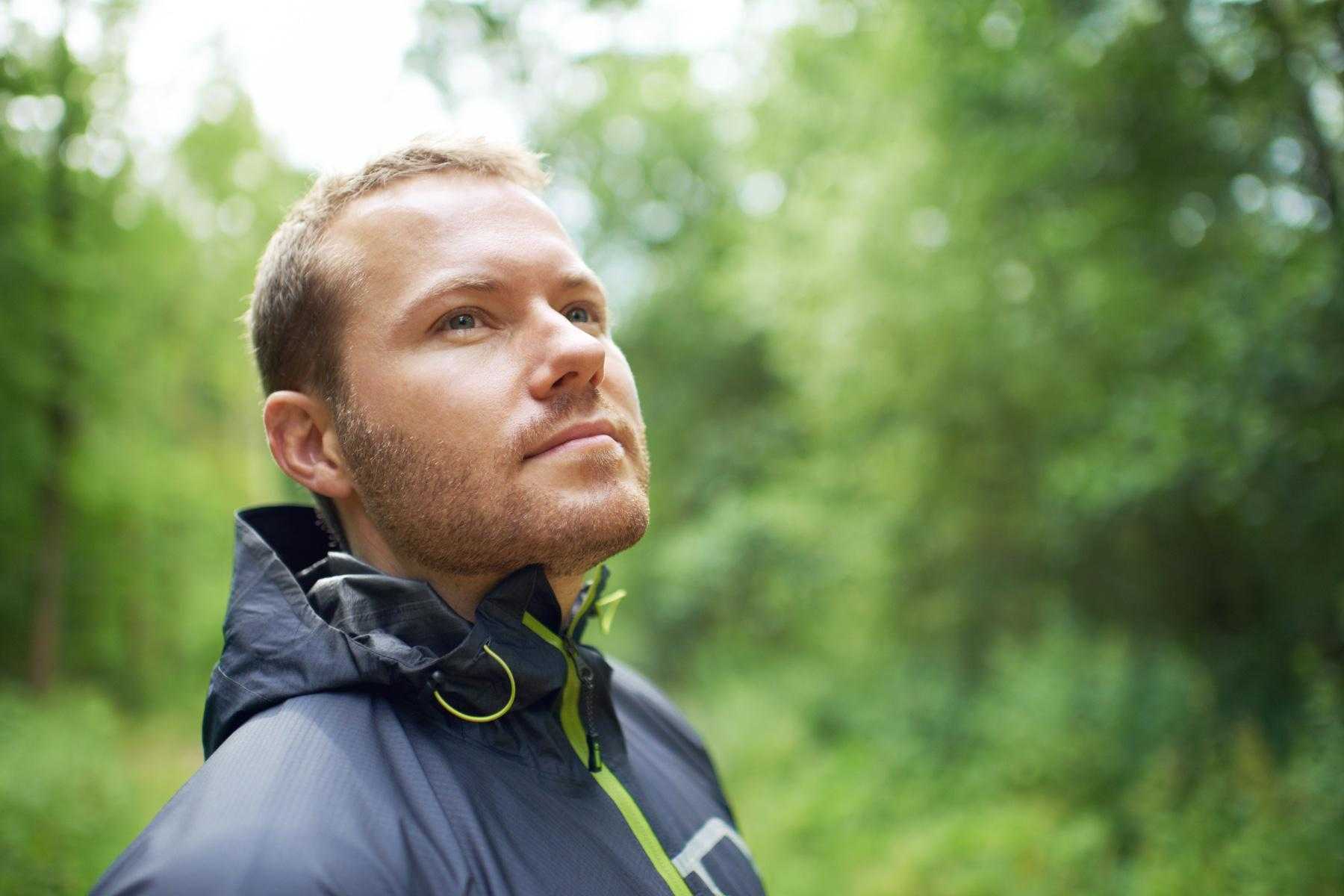 A man standing in a forest looking out into the distance.