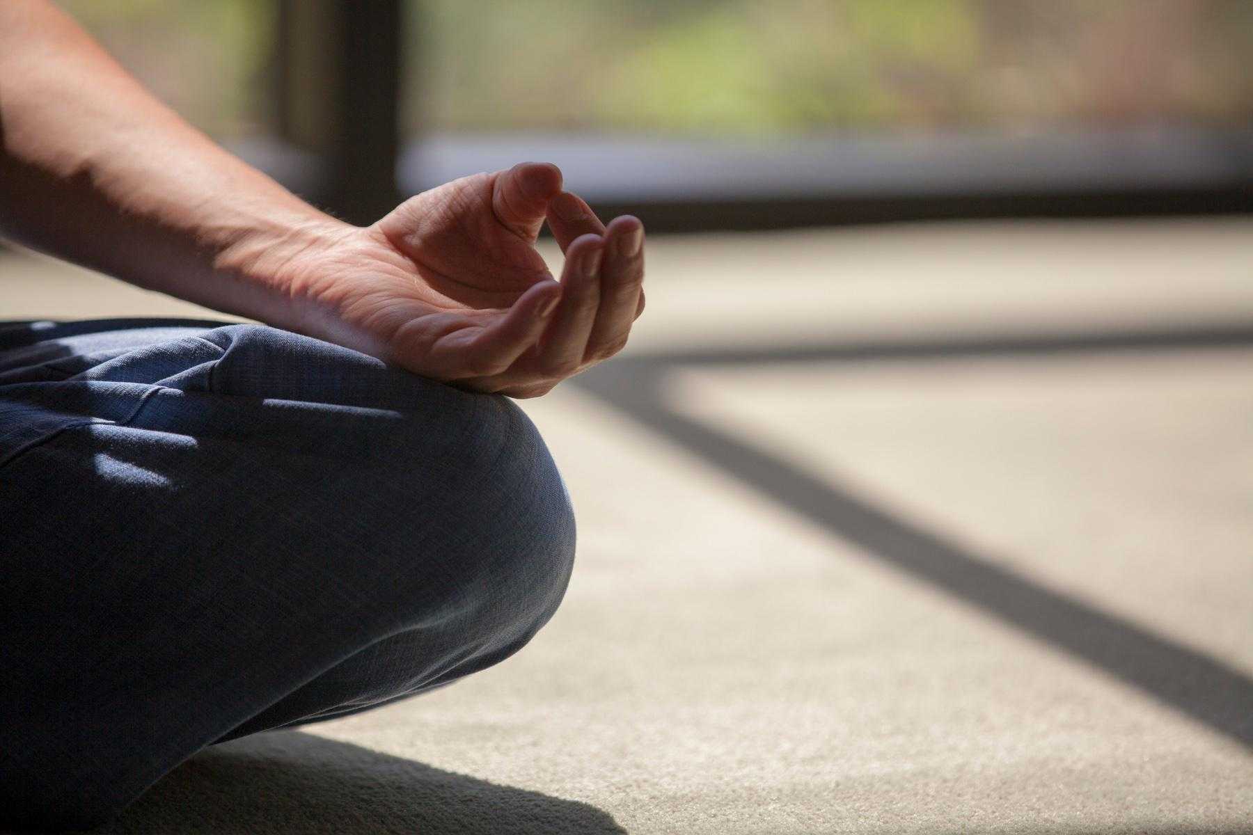 Close-up of hand in meditation position on leg.