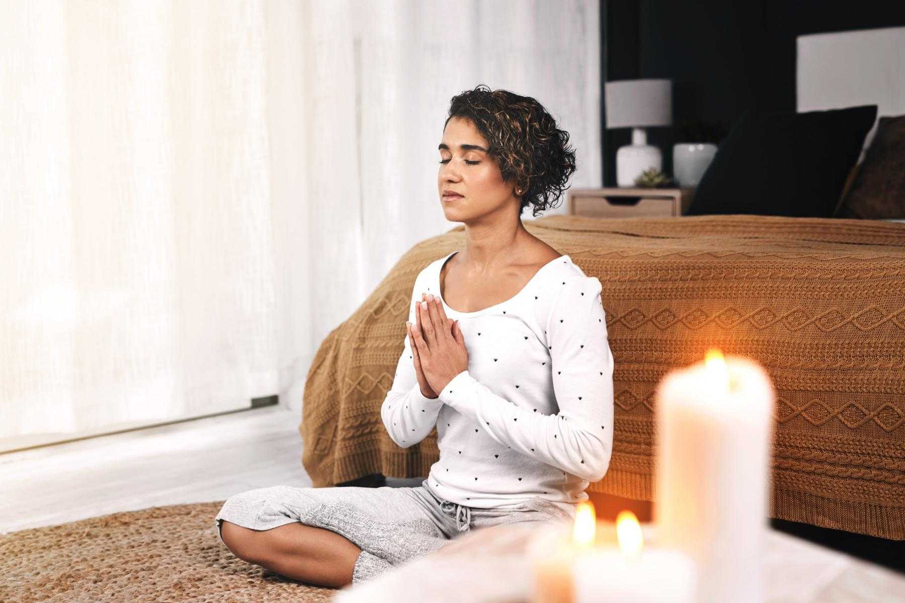 Woman meditating in her bedroom.