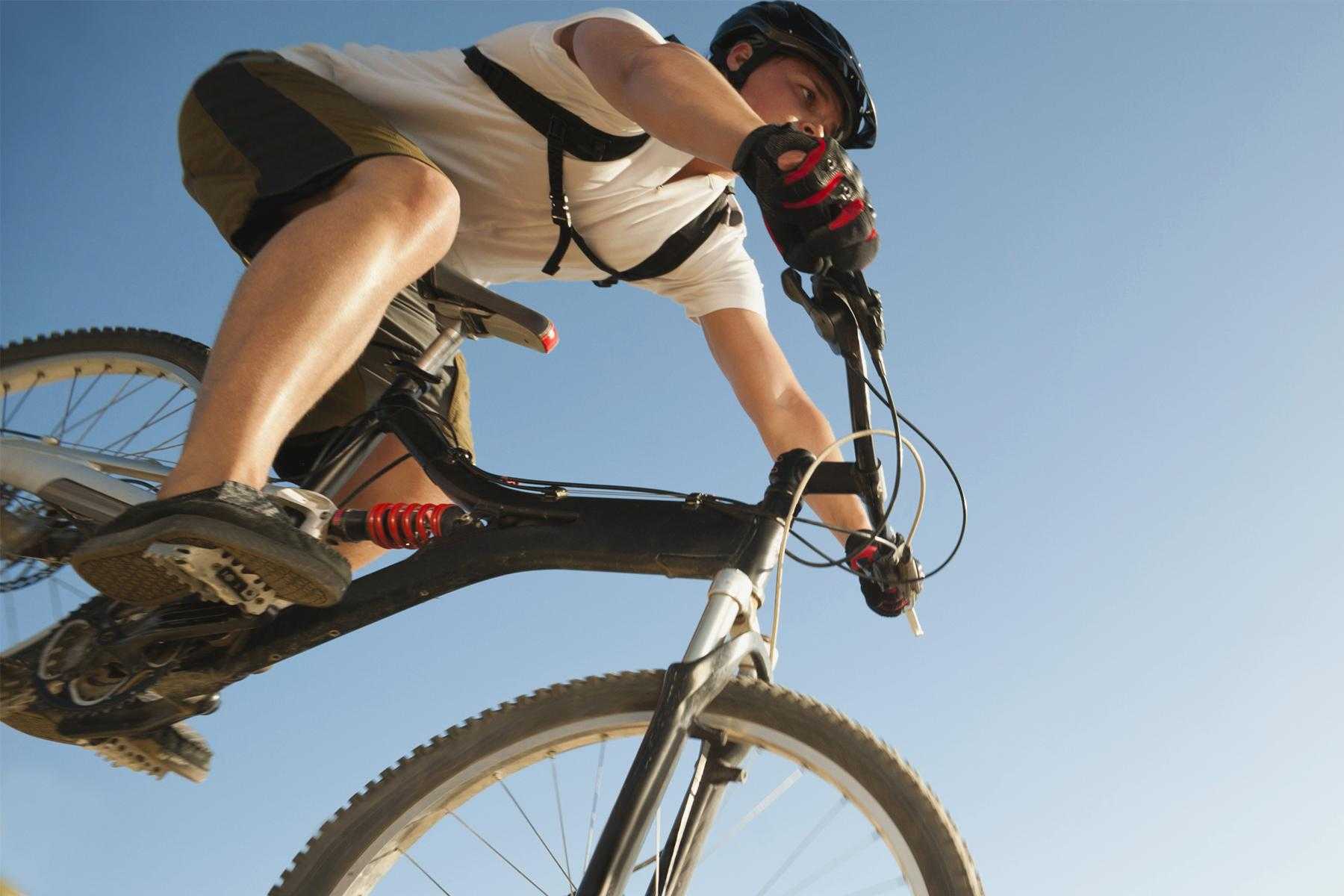 Close-up of cyclist riding bike outside against blue sky.