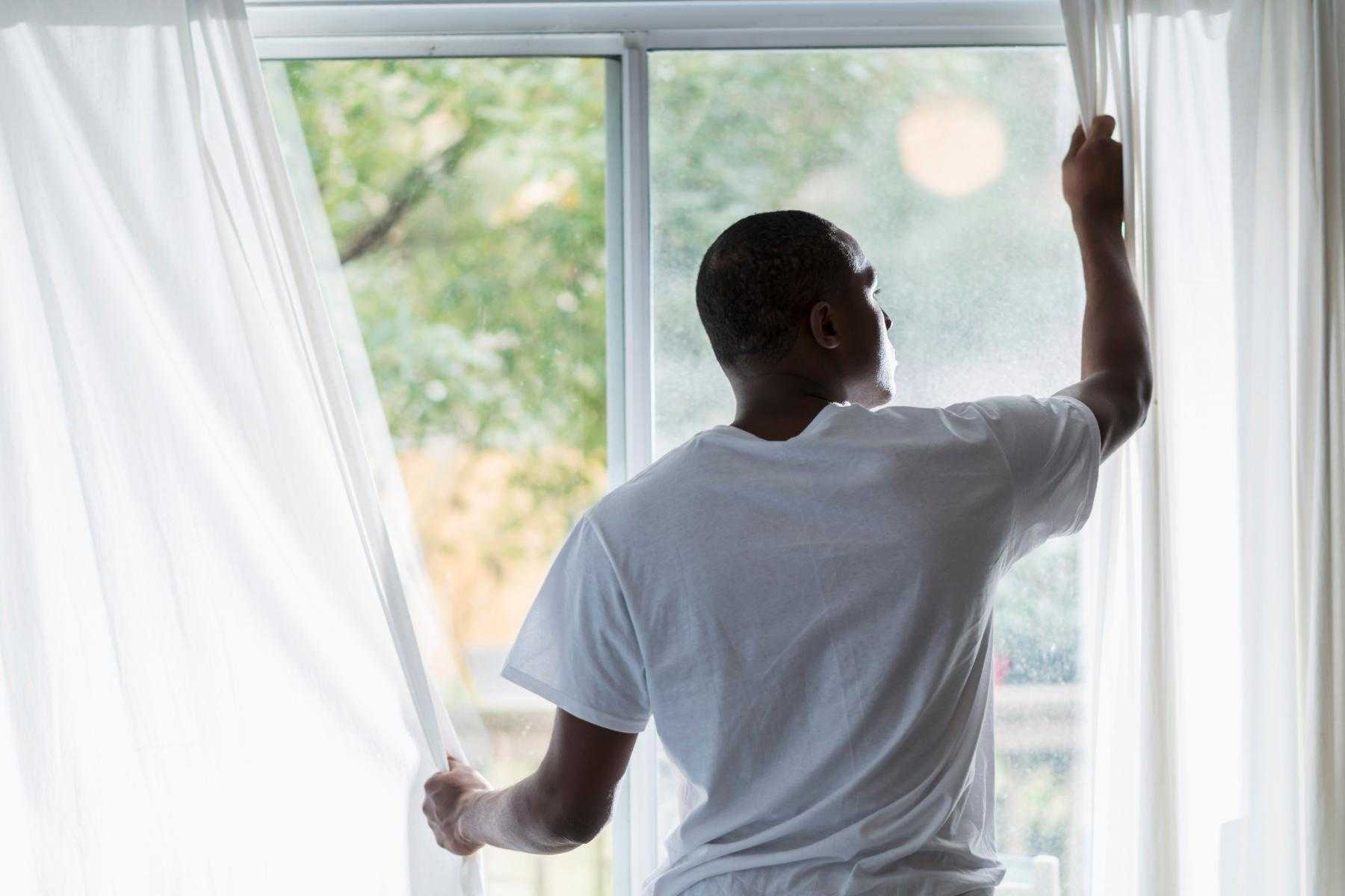 Man pulling curtains closed.