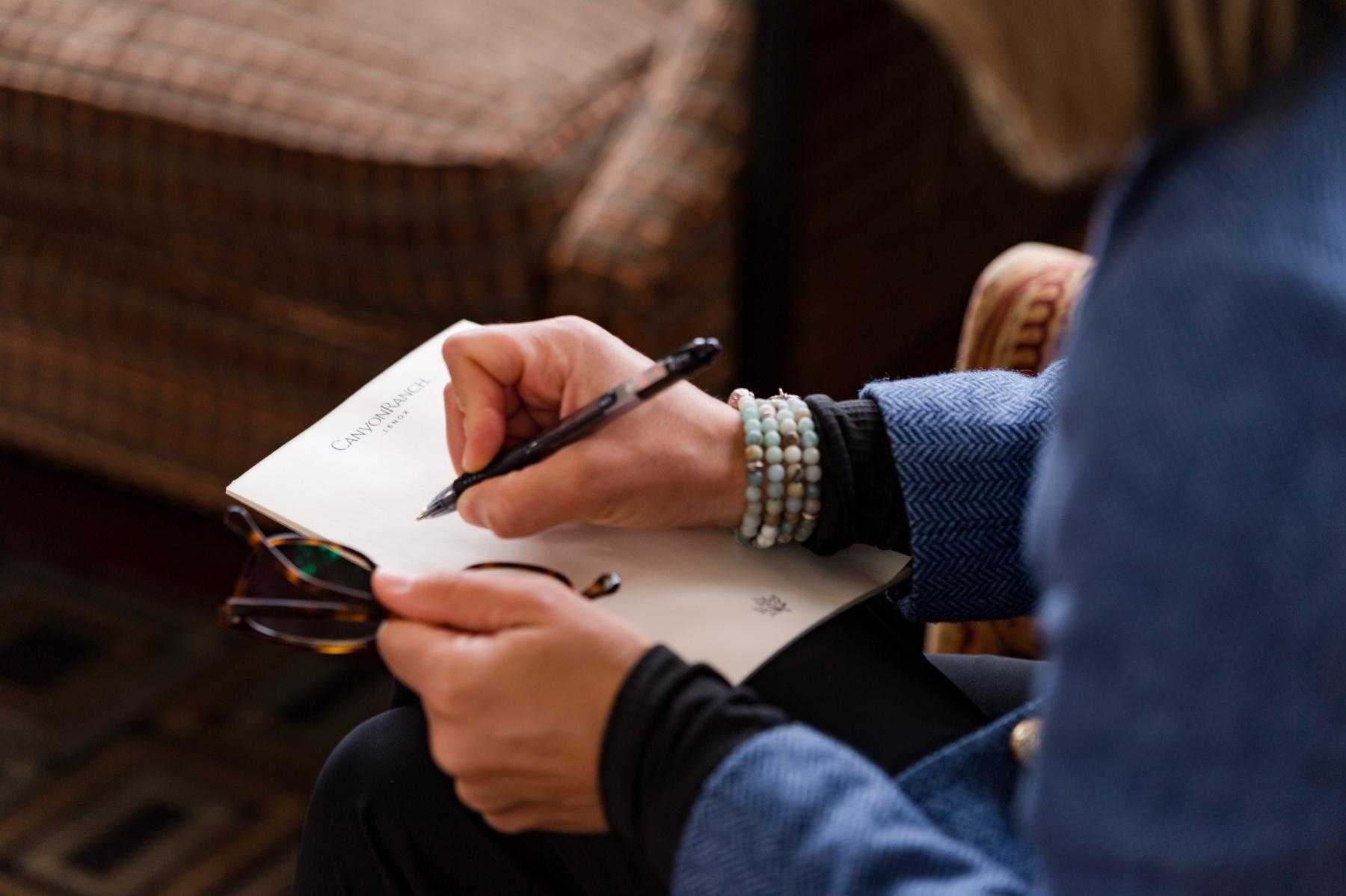 Close-up of woman's hand as she writes with a pen on a pad of paper.