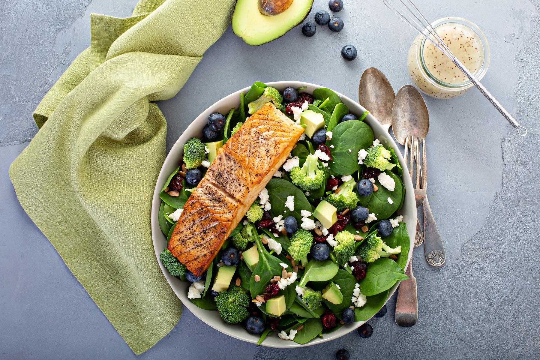 Overhead image of a bowl filled with a spinach salad with salmon on it.