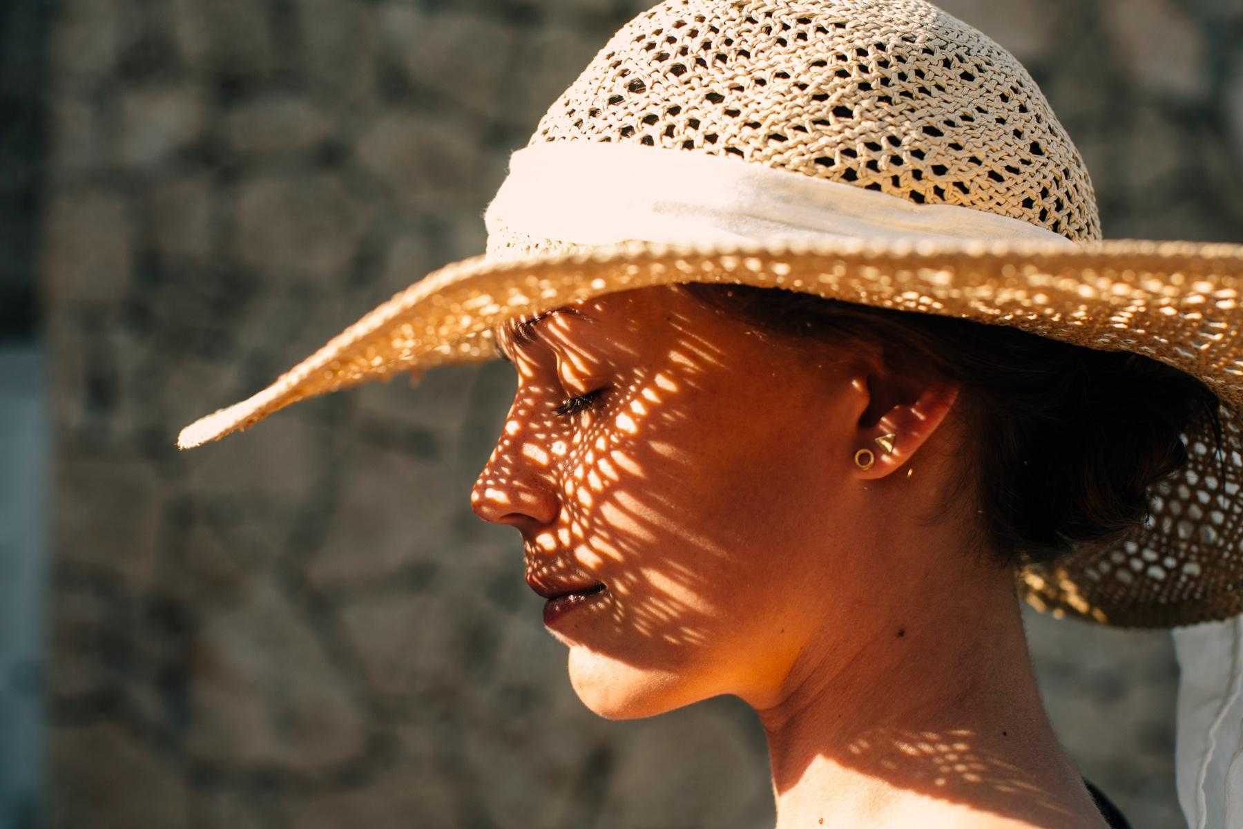 Close-up of a woman from the side wearing a sunhat that is casting a shadow on her face.