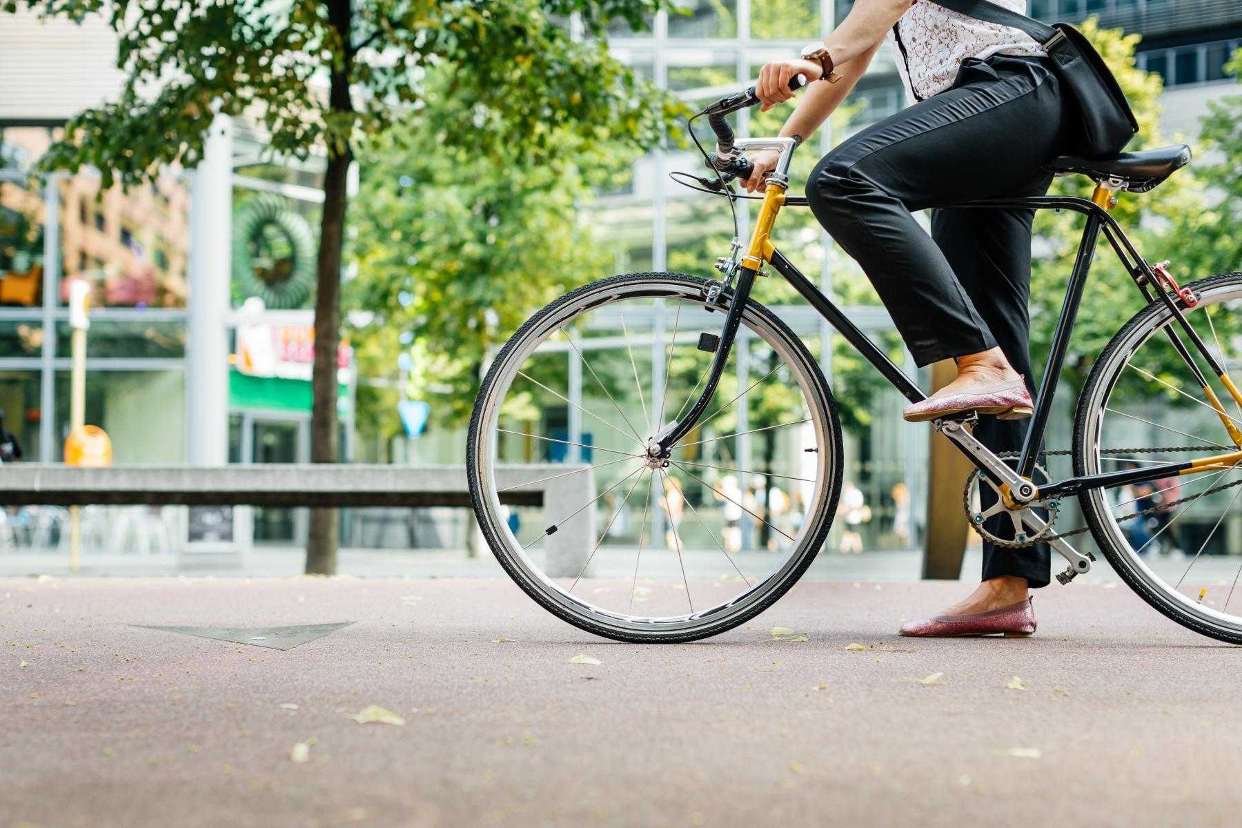 close-up from waist down of a woman in work clothes on a bike commute