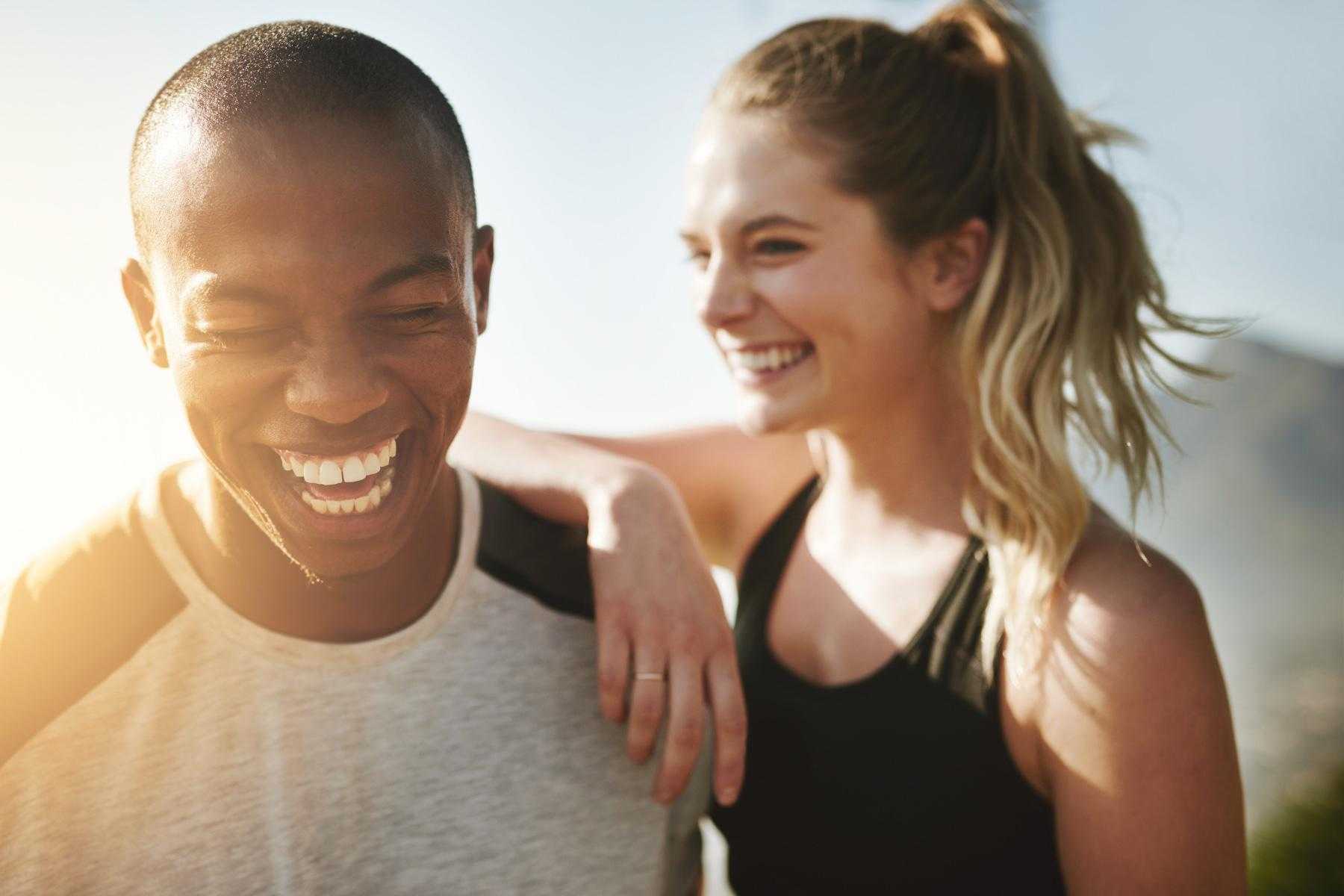 close-up on a smiling young man and woman as she leans her arm on his shoulder