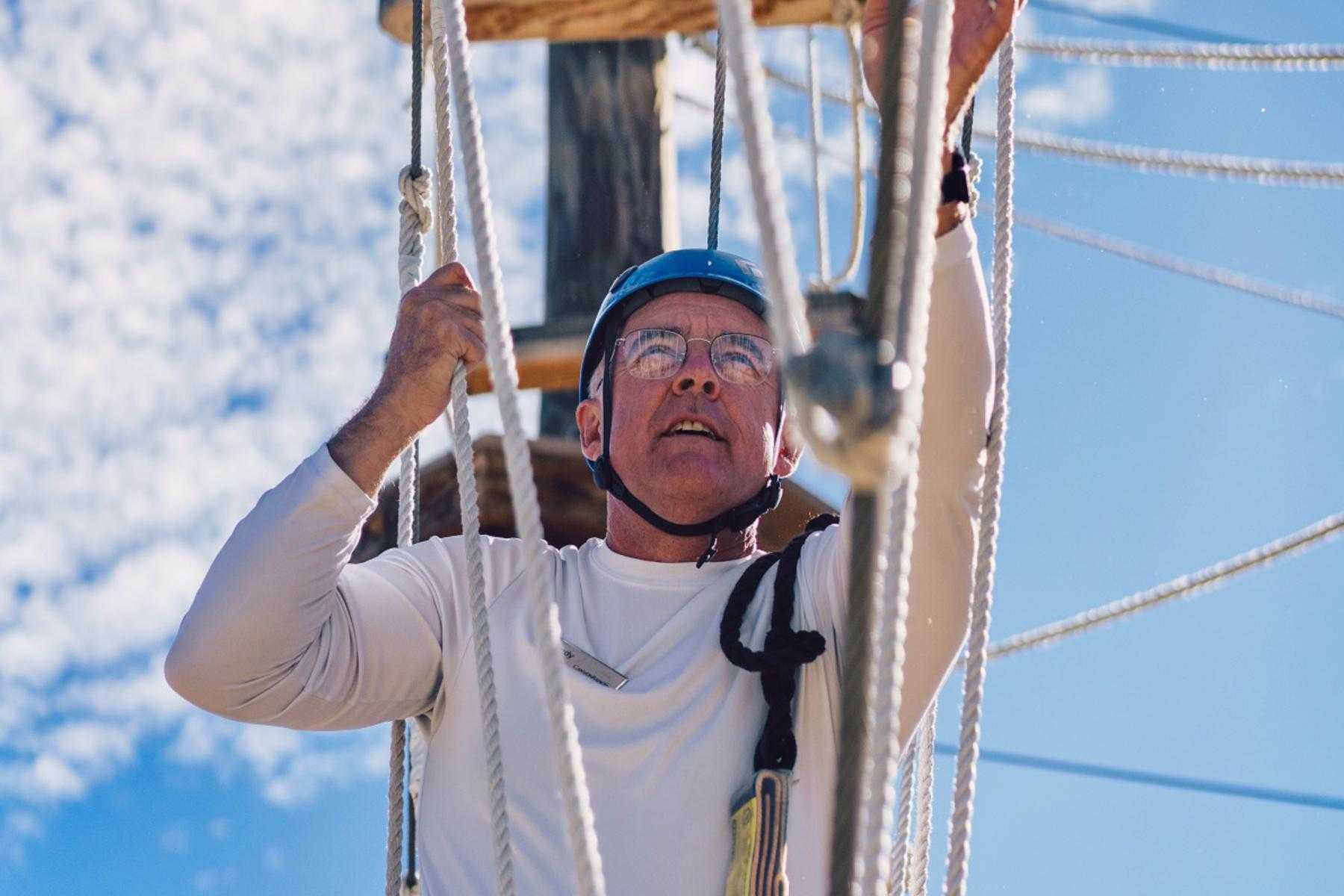 A mature man climbing a ropes course.
