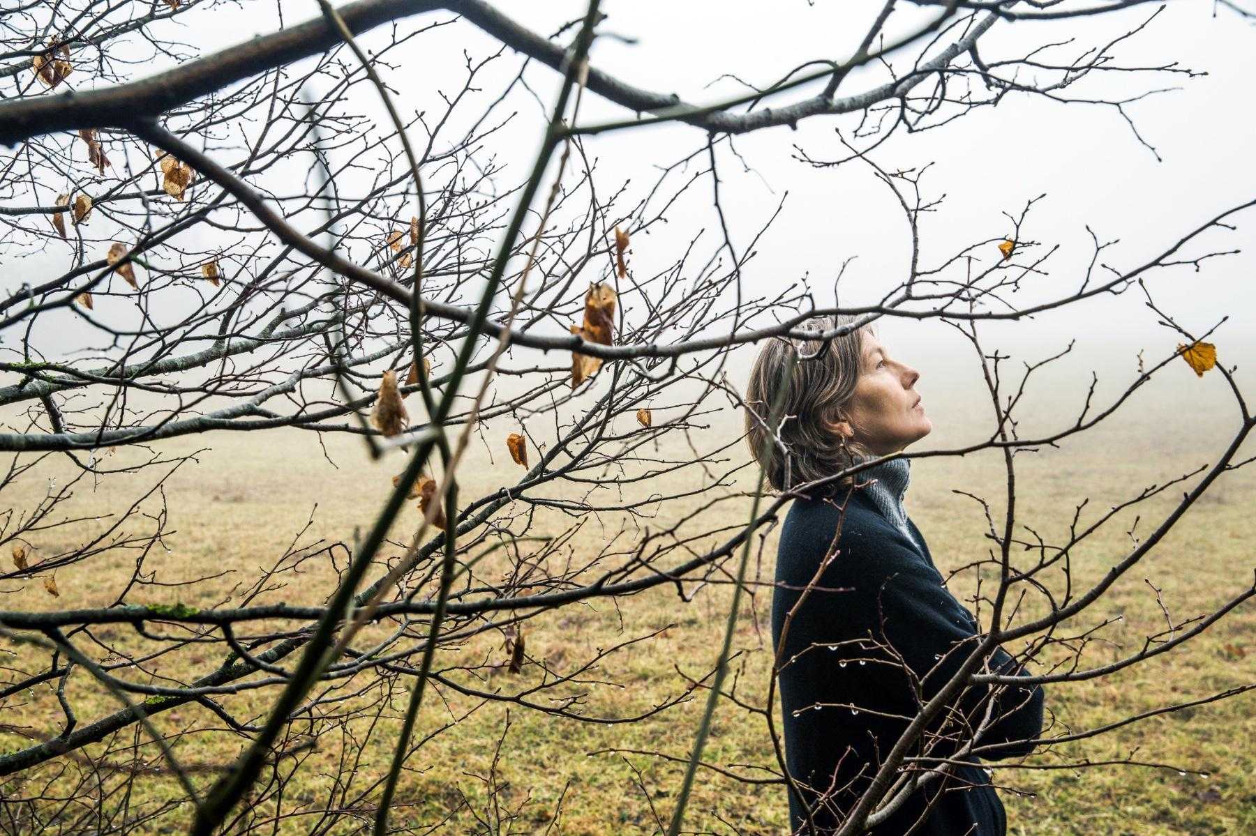 Woman standing next to a tree.
