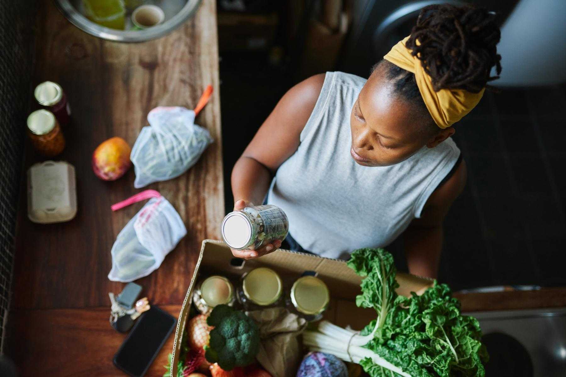 Overhead shot of woman reading food label on jar.