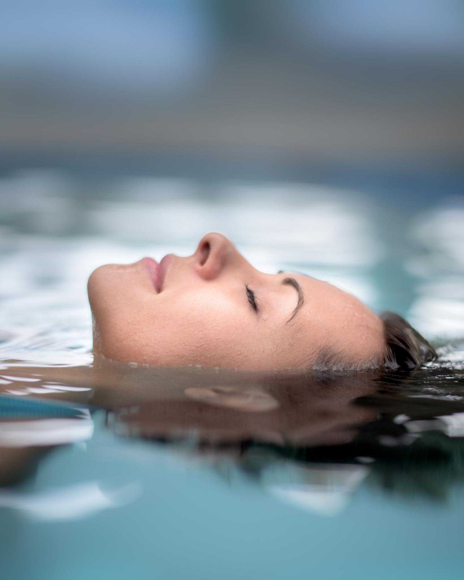 A woman smiling and splashing in the pool