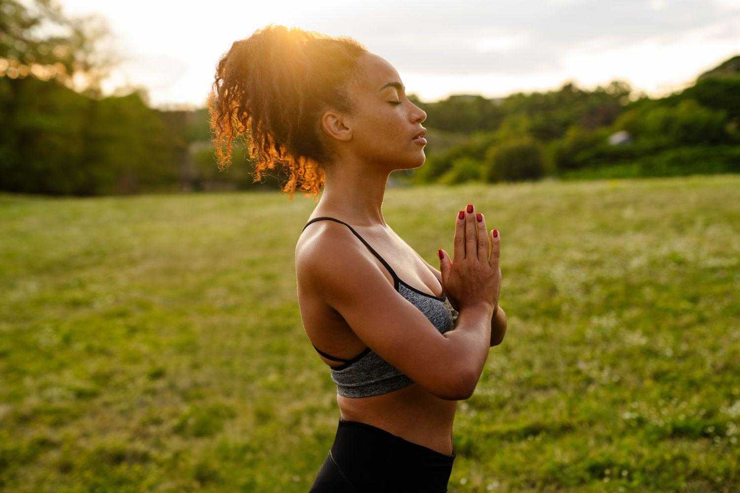 a woman meditating in a summer sunrise