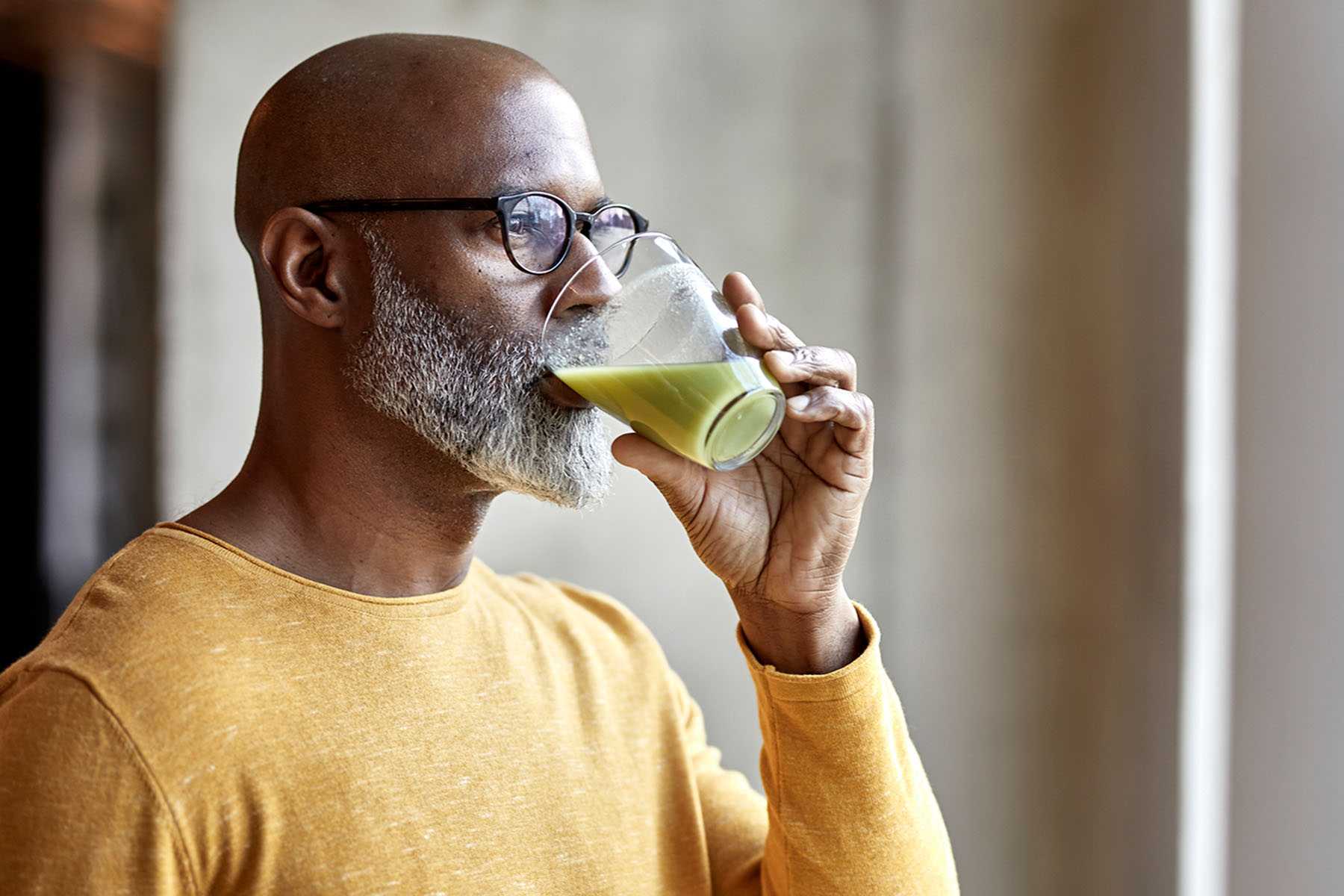 A man drinking a green health smoothie