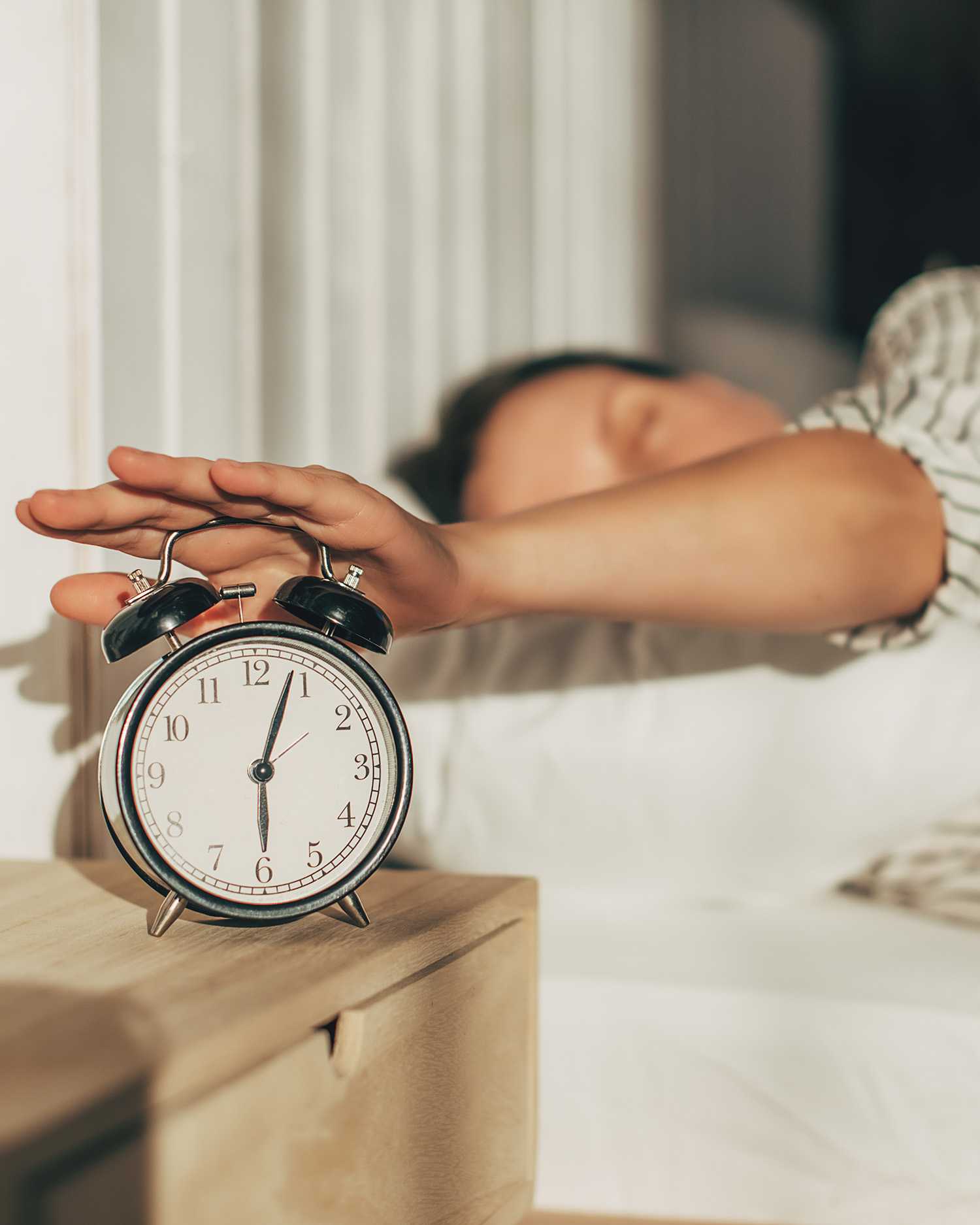 a woman turning off an alarm clock