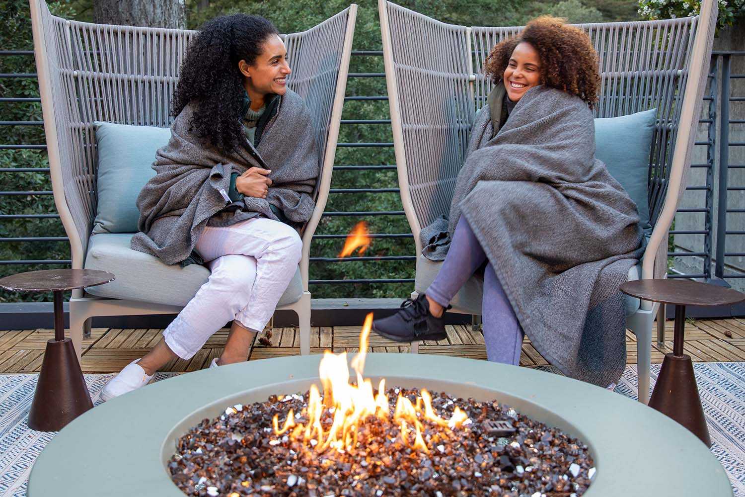 two women chatting at around a fire
