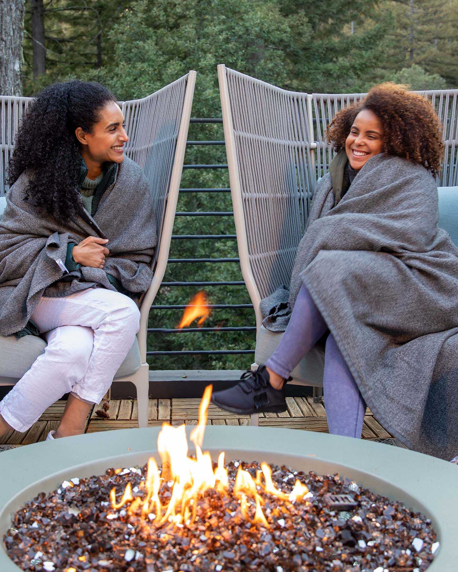two women chatting at around a fire