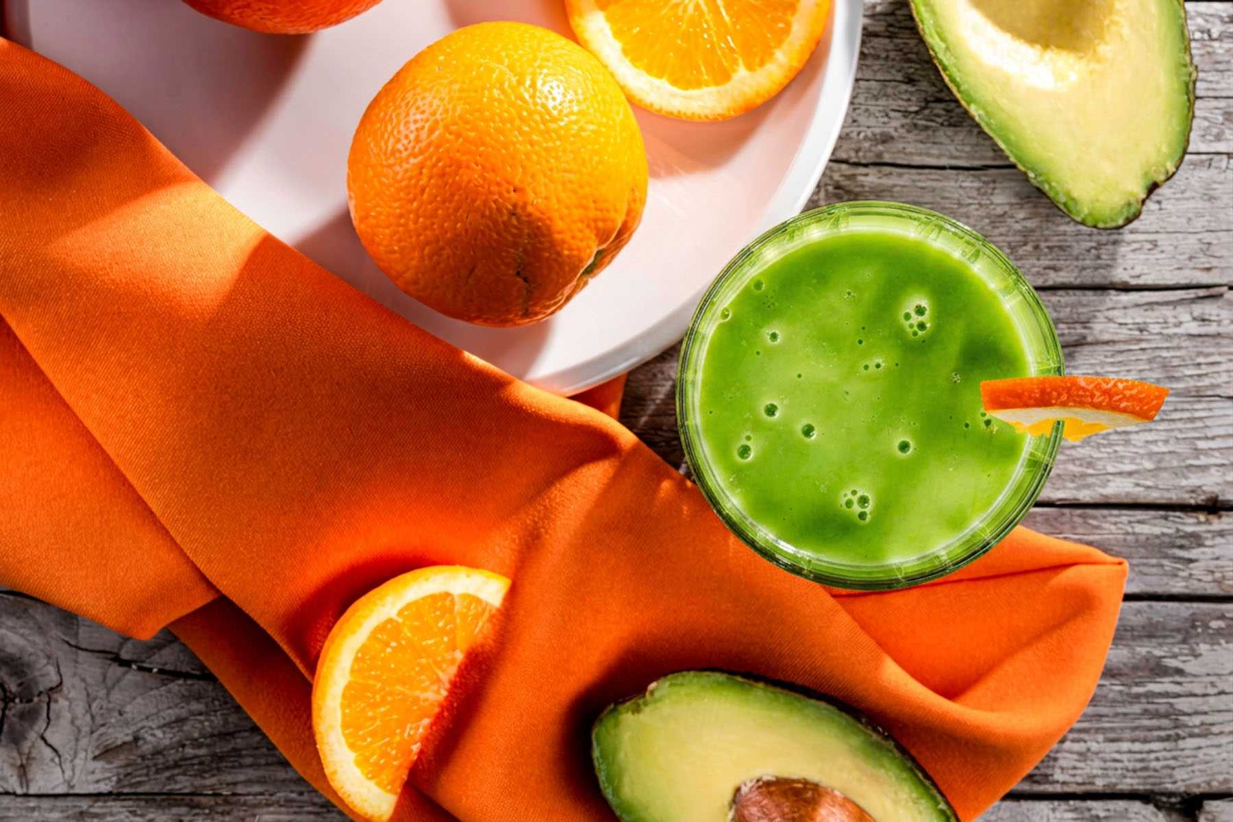 a green smoothie surrounded by avocado and citrus