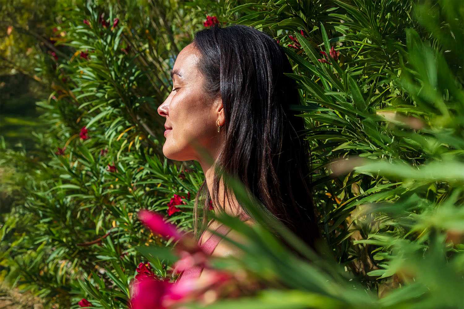 Woman Standing With Closed Eyes Between Green Bushes and Pink Flowers 