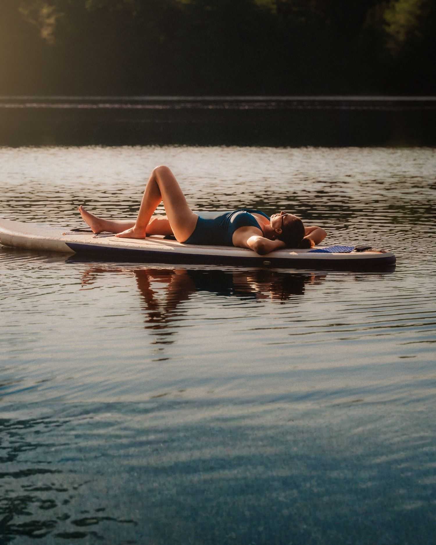 A woman on a lake on a paddle bard. 