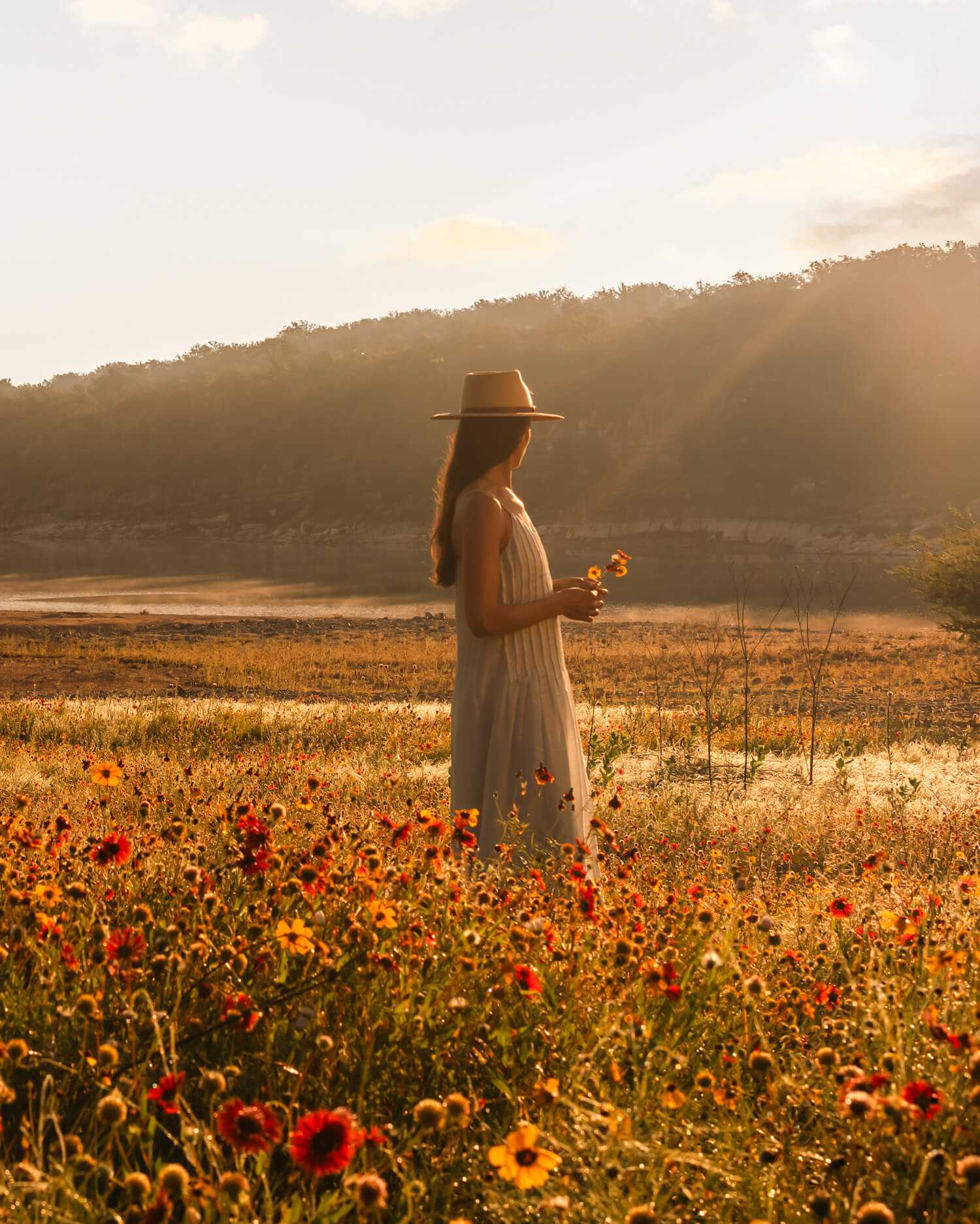 woman standing in field of flowers in hill country