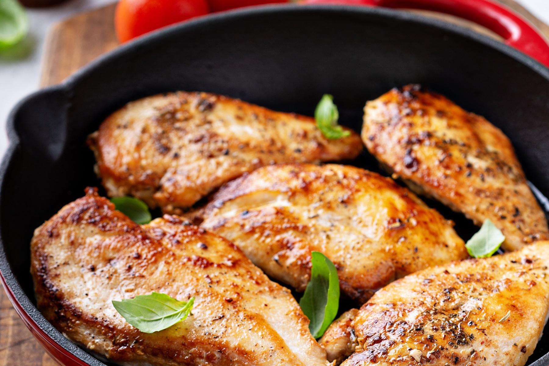 A pan of 5 pieces of chicken cooking.