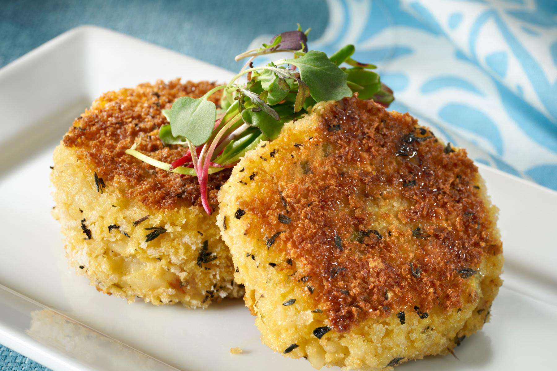 Two risotto cakes on a white dish.