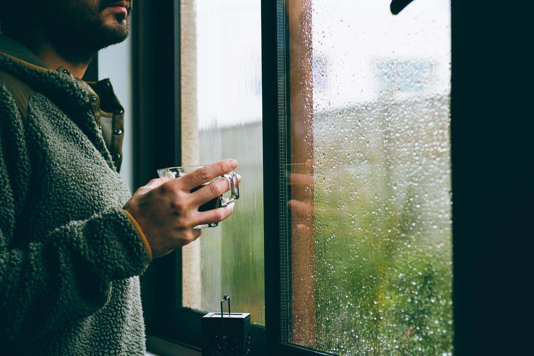 Woman drinking a cup of coffee and looking outside her window.