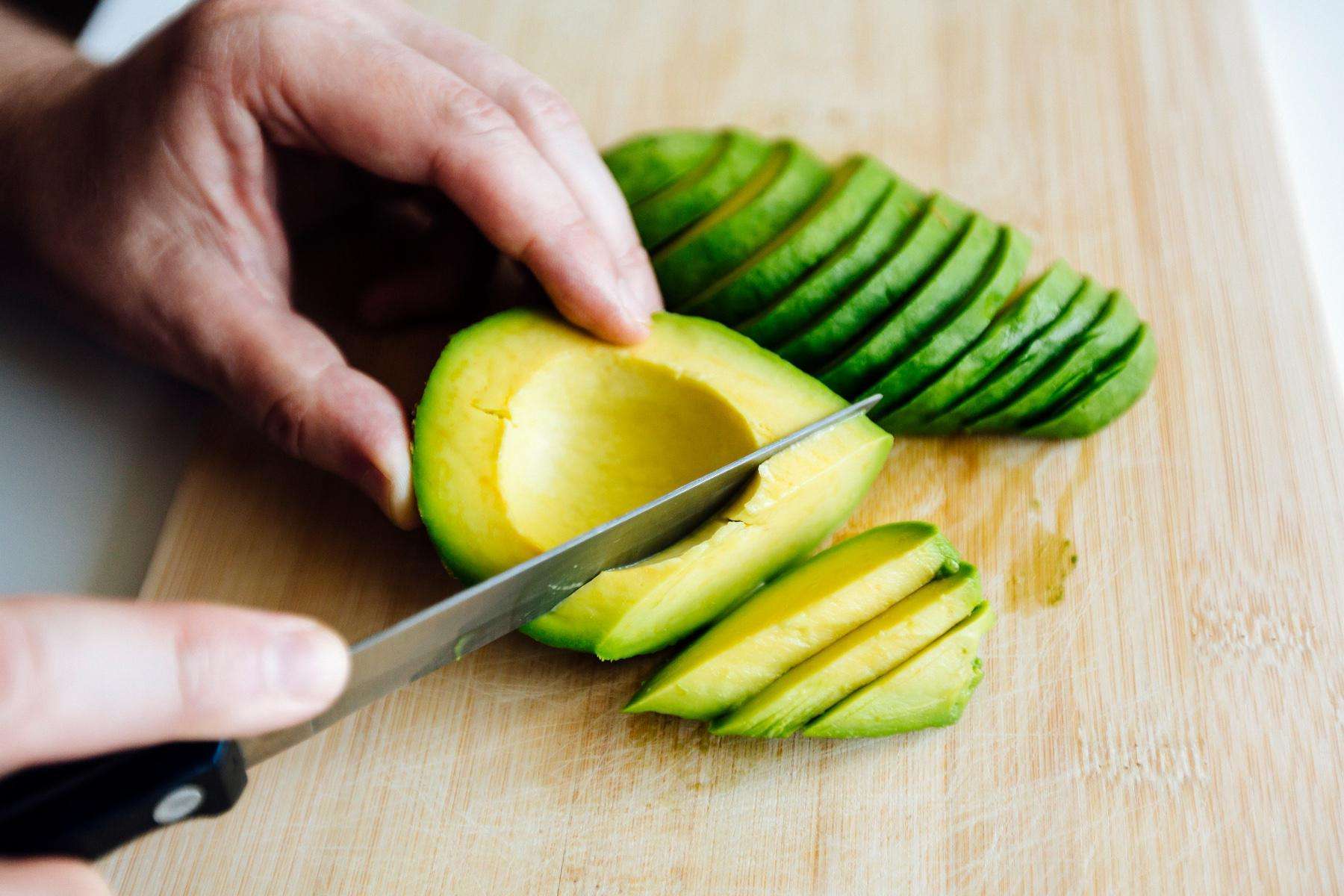 Close-up of knife cutting through avocado.
