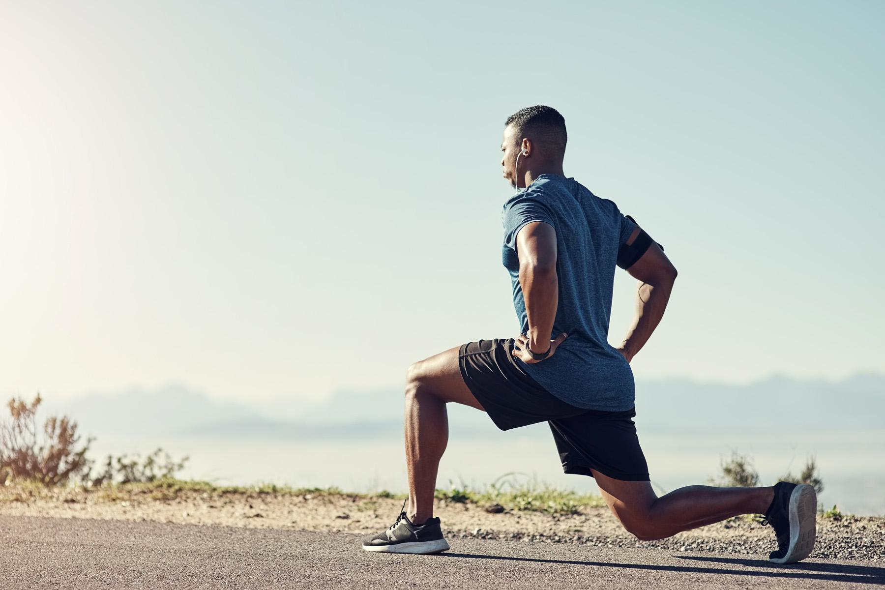 Man outside doing lunge on road.