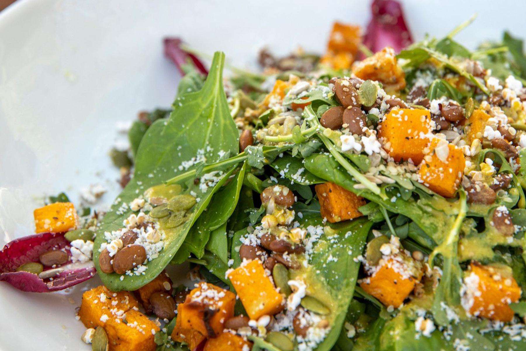Close-up of salad with spinach, butternut squash, and cheese.