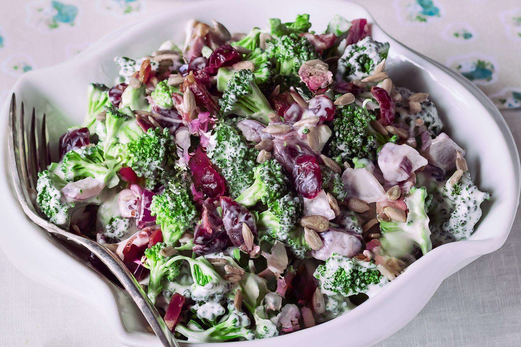 A large serving bowl of broccoli cranberry salad with dressing